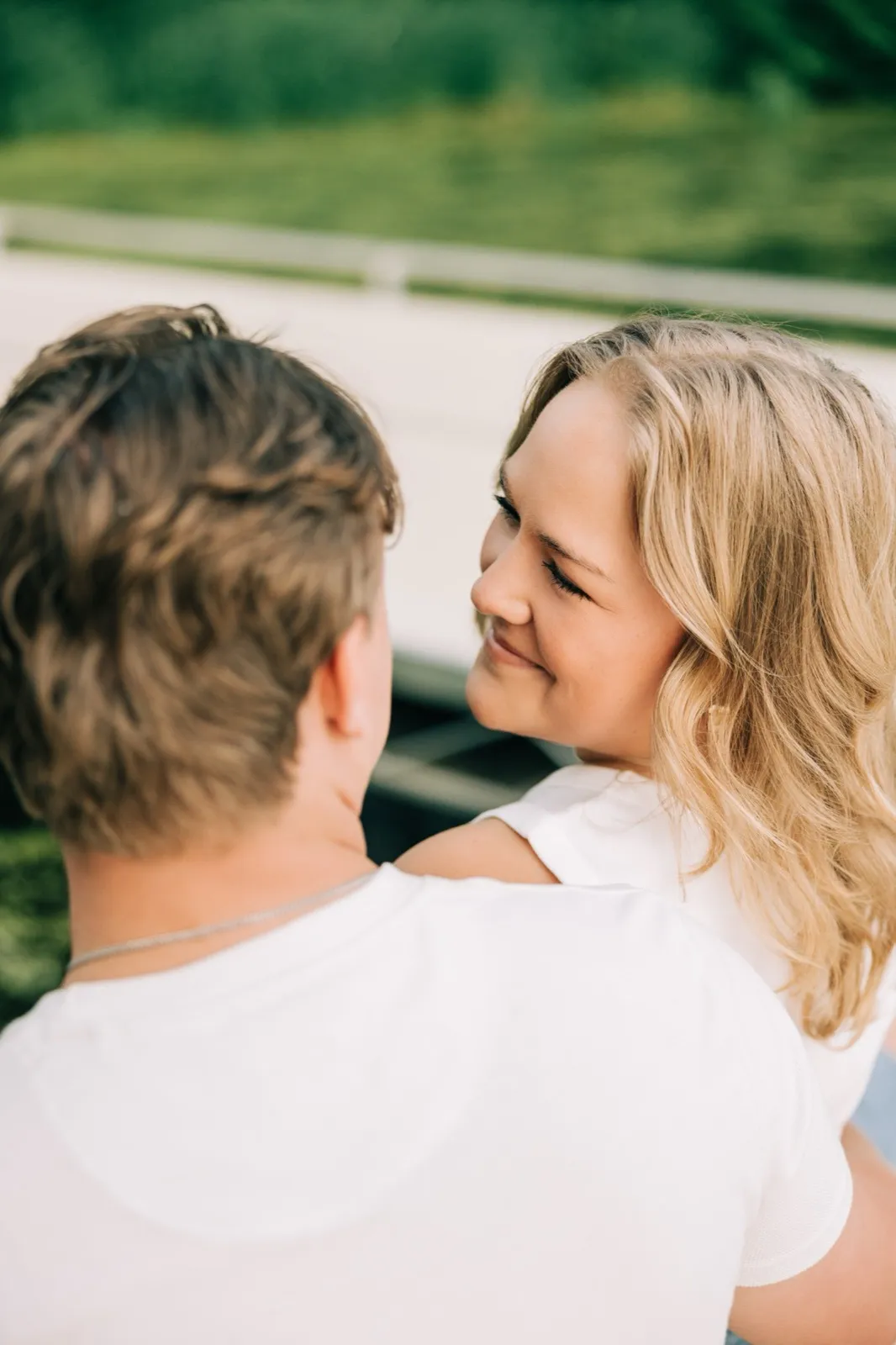 Abby and Anthony sit forehead to forehead on the dock with a rack of canoes and the wooded shore behind them — Tim Larsen Photography