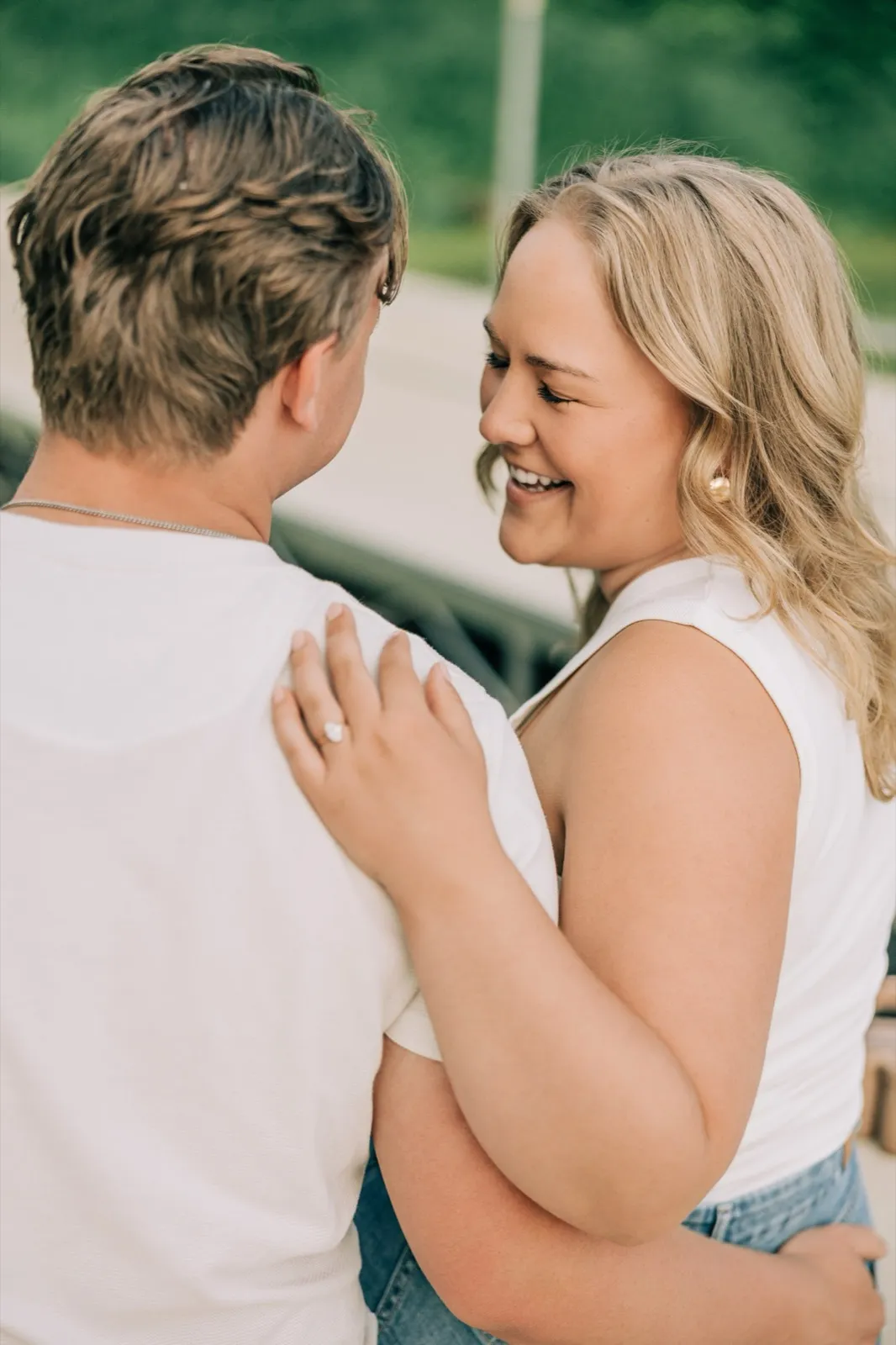 Anthony lifts Abby off her feet on the Lake Auburn dock as she laughs, the calm lake stretching behind them — Tim Larsen Photography