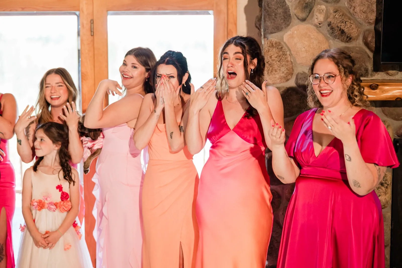 Bridesmaids and flower girl reacting with tears and laughter as they see the bride for the first time