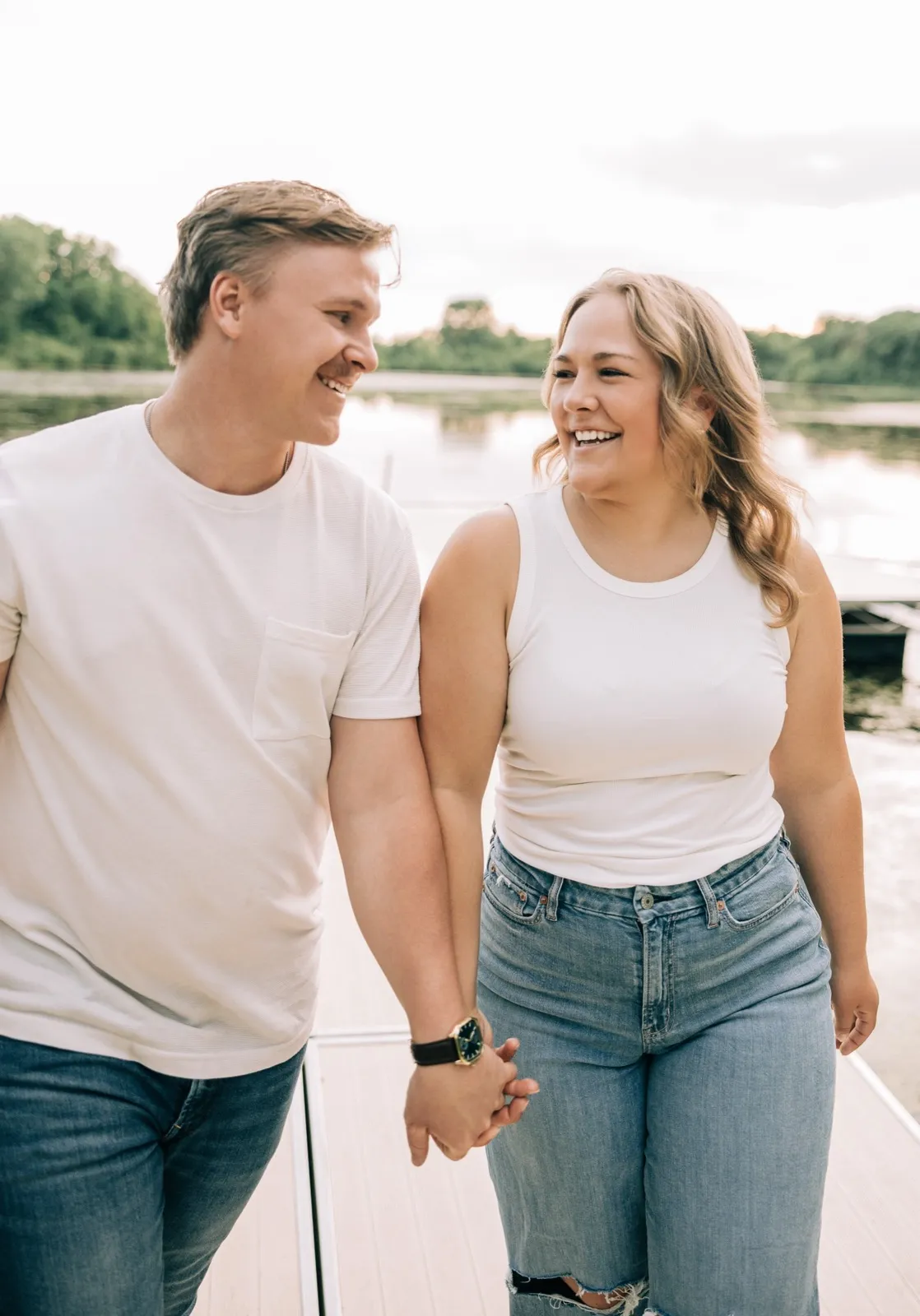 Abby and Anthony walk hand in hand down the Lake Auburn dock, laughing — Tim Larsen Photography