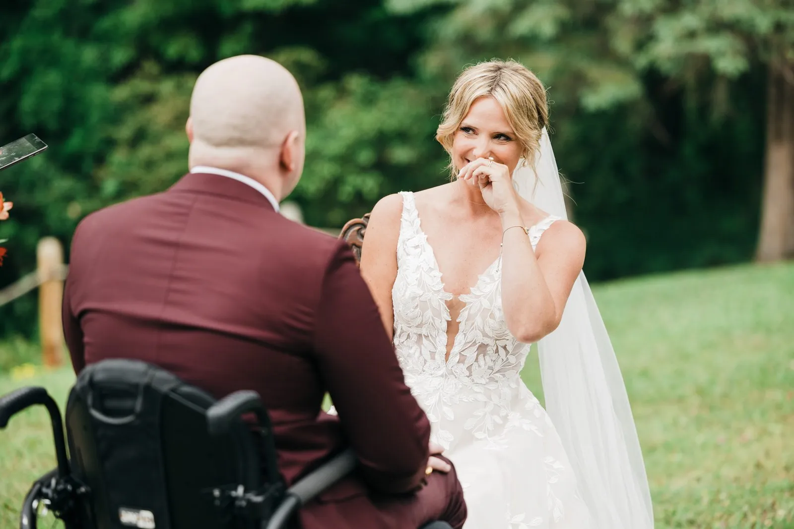 Jenna presses a hand to her mouth, welling up mid-vows, with Joe's burgundy shoulder in the foreground at their lakeside ceremony at Chase on the Lake. — Tim Larsen Photography, Brainerd Lakes MN