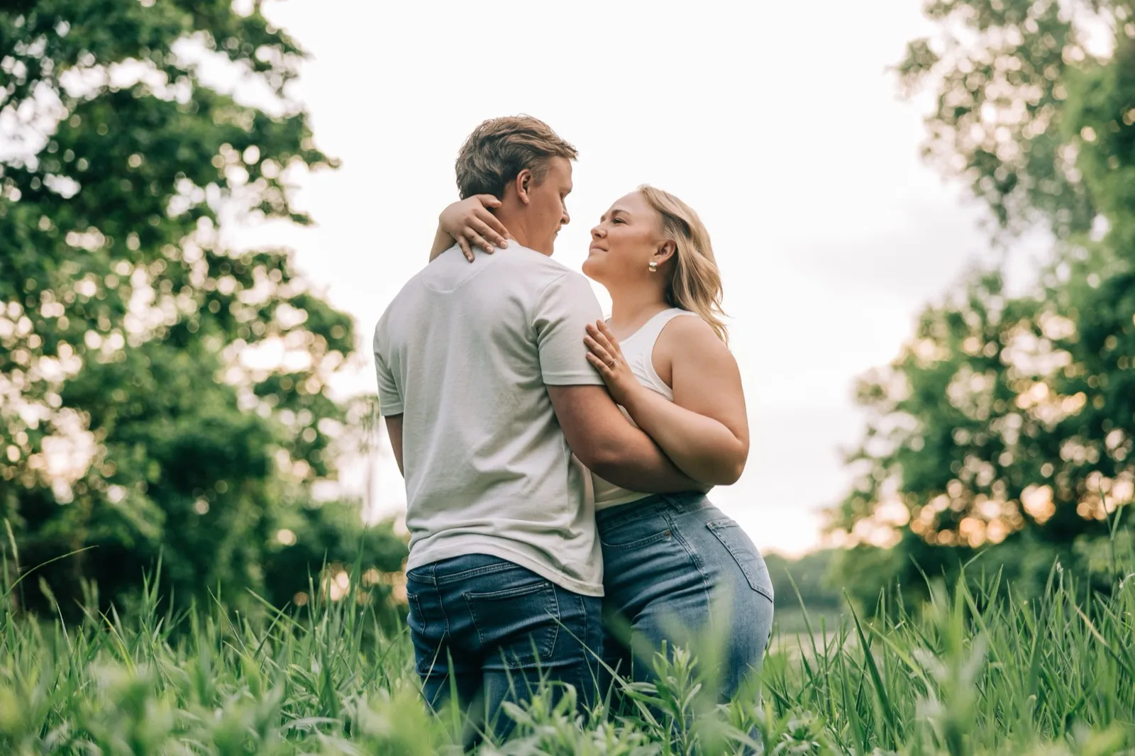 Abby and Anthony stand forehead to forehead in the tall grass as the sun sets at Carver Park — Tim Larsen Photography