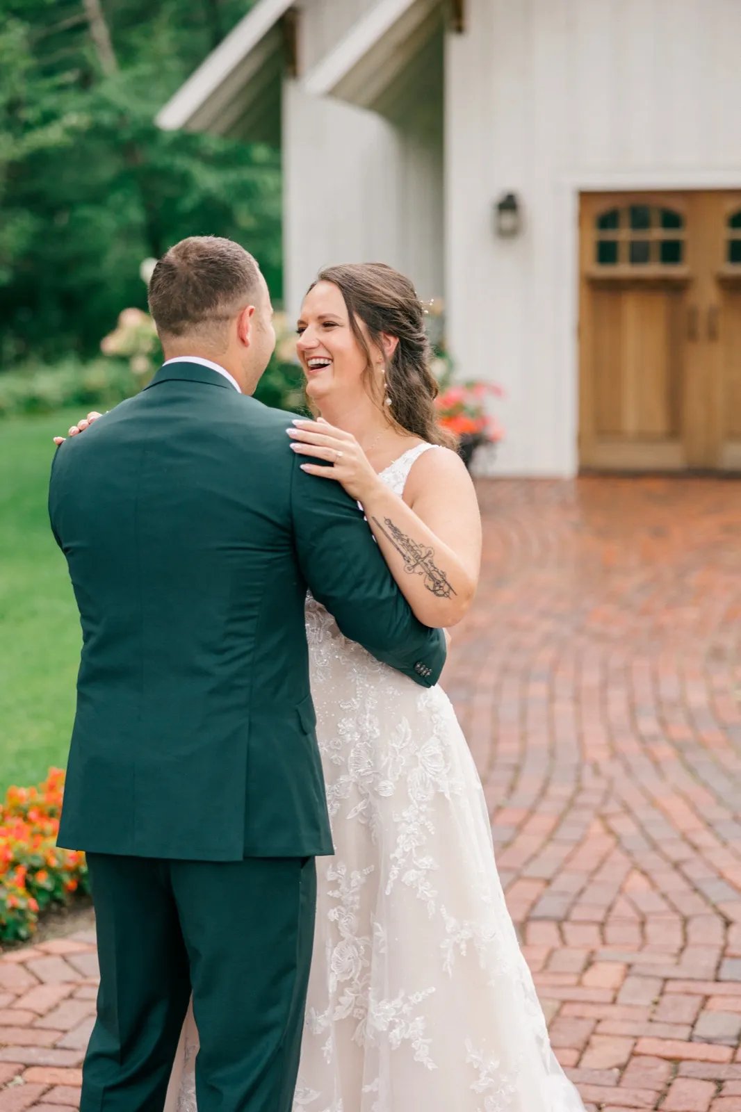 Chelsea laughs brightly with her hand on Eric's shoulder during their first look outside the lodge, her embroidered gown and forearm tattoo visible — Tim Larsen Photography, Brainerd Lakes MN