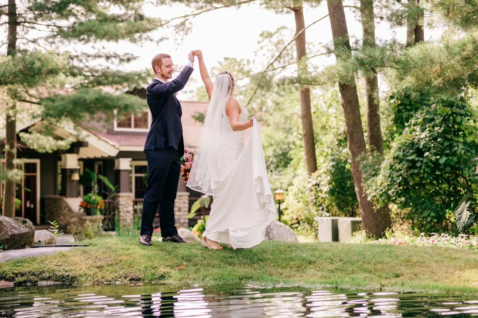 Mats twirls Monika beside a small pond on the lawn outside Grand View Lodge, her veil and dress trailing in motion — Tim Larsen Photography, Brainerd Lakes MN
