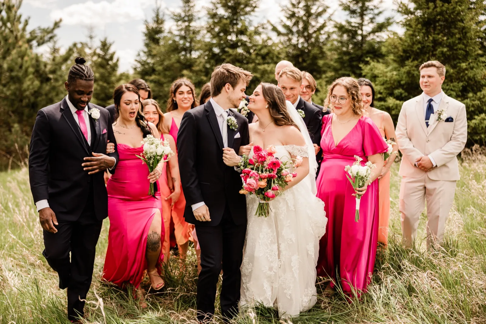 Full bridal party walking through a forest clearing at Pine Peaks Event Center