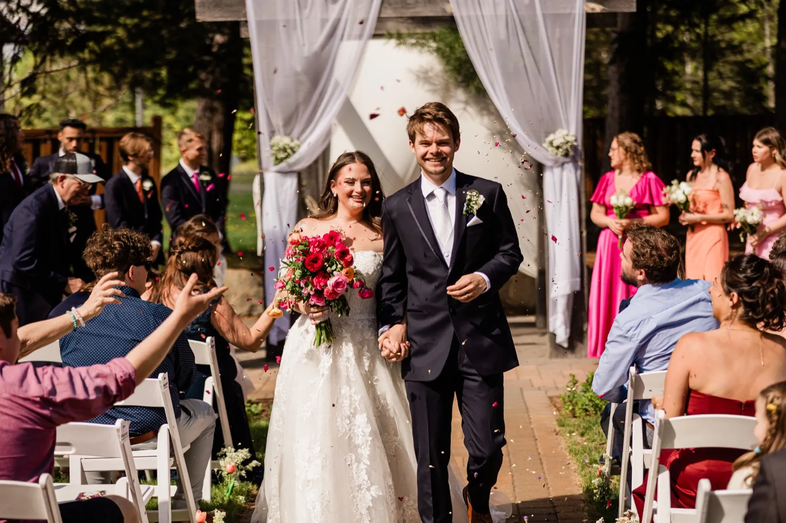 Recessional with petals flying around the bride and groom as they walk hand-in-hand down the aisle