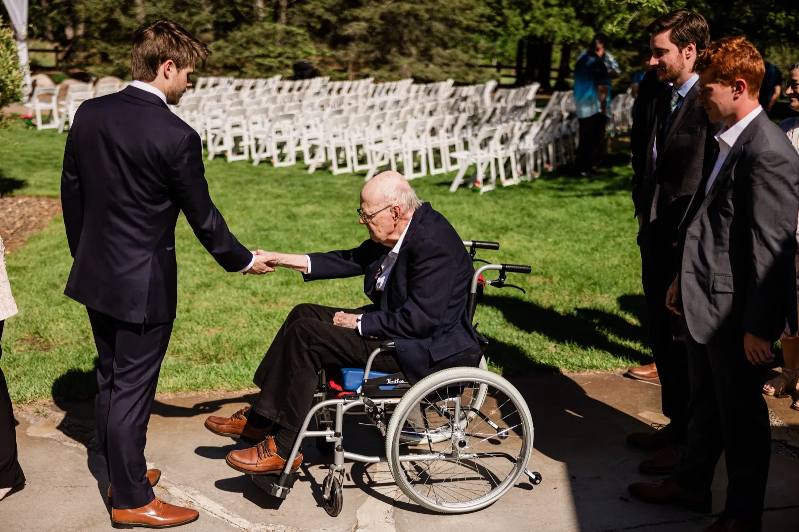 Groom shaking hands with an elder guest in a wheelchair before the ceremony