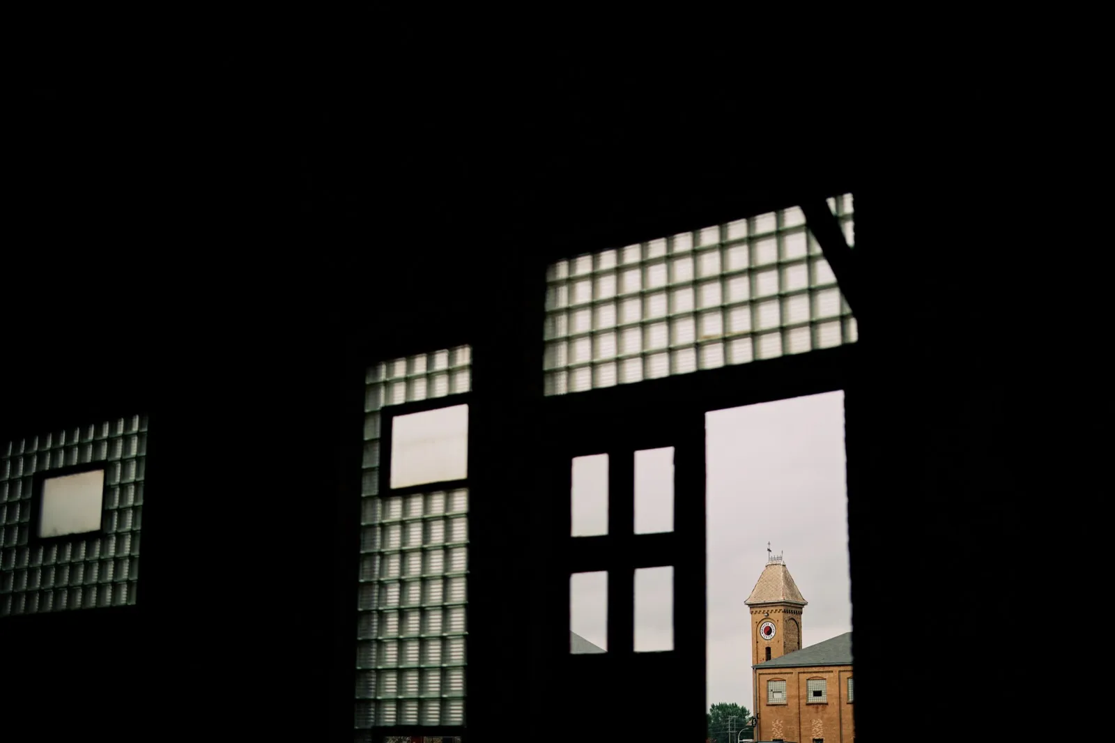 A dark industrial doorway and grid windows frame Northern Pacific Center's brick clock tower during Maggie and Craig's wedding day — Tim Larsen Photography, Brainerd Lakes MN