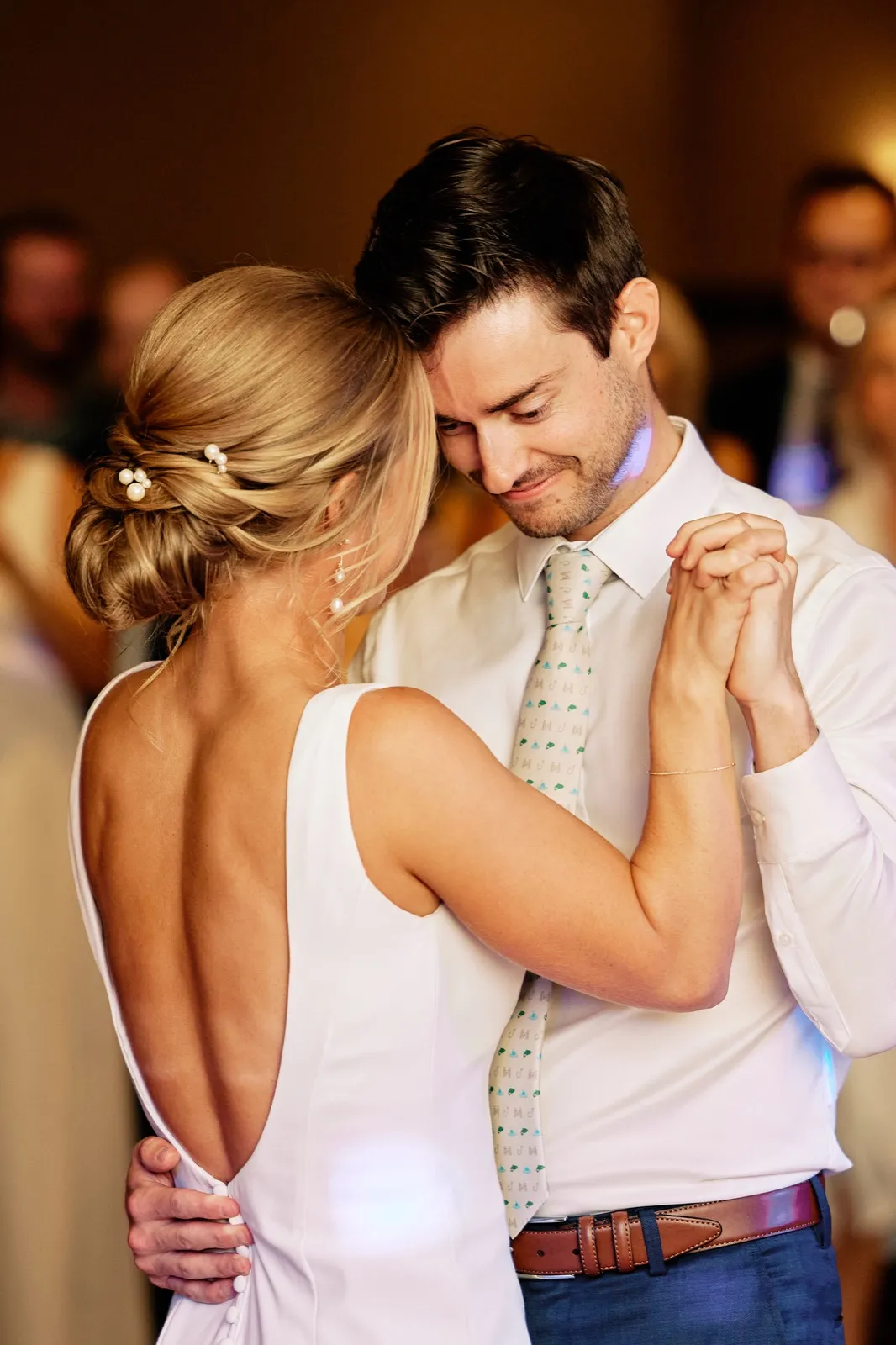 The groom rests his forehead against the bride's temple as they hold clasped hands during their first dance in the Grand Ballroom