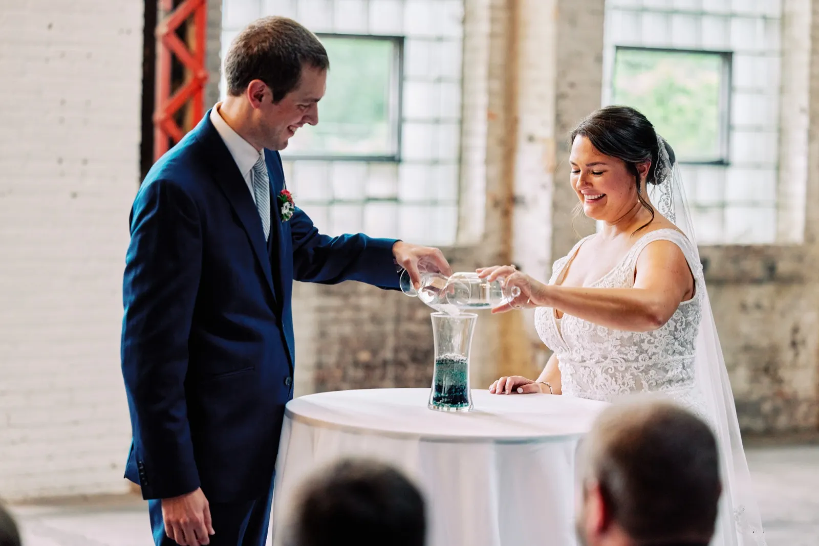 Maggie and Craig pour colored sand into a glass vessel together during their ceremony in the brick hall — Tim Larsen Photography, Brainerd Lakes MN