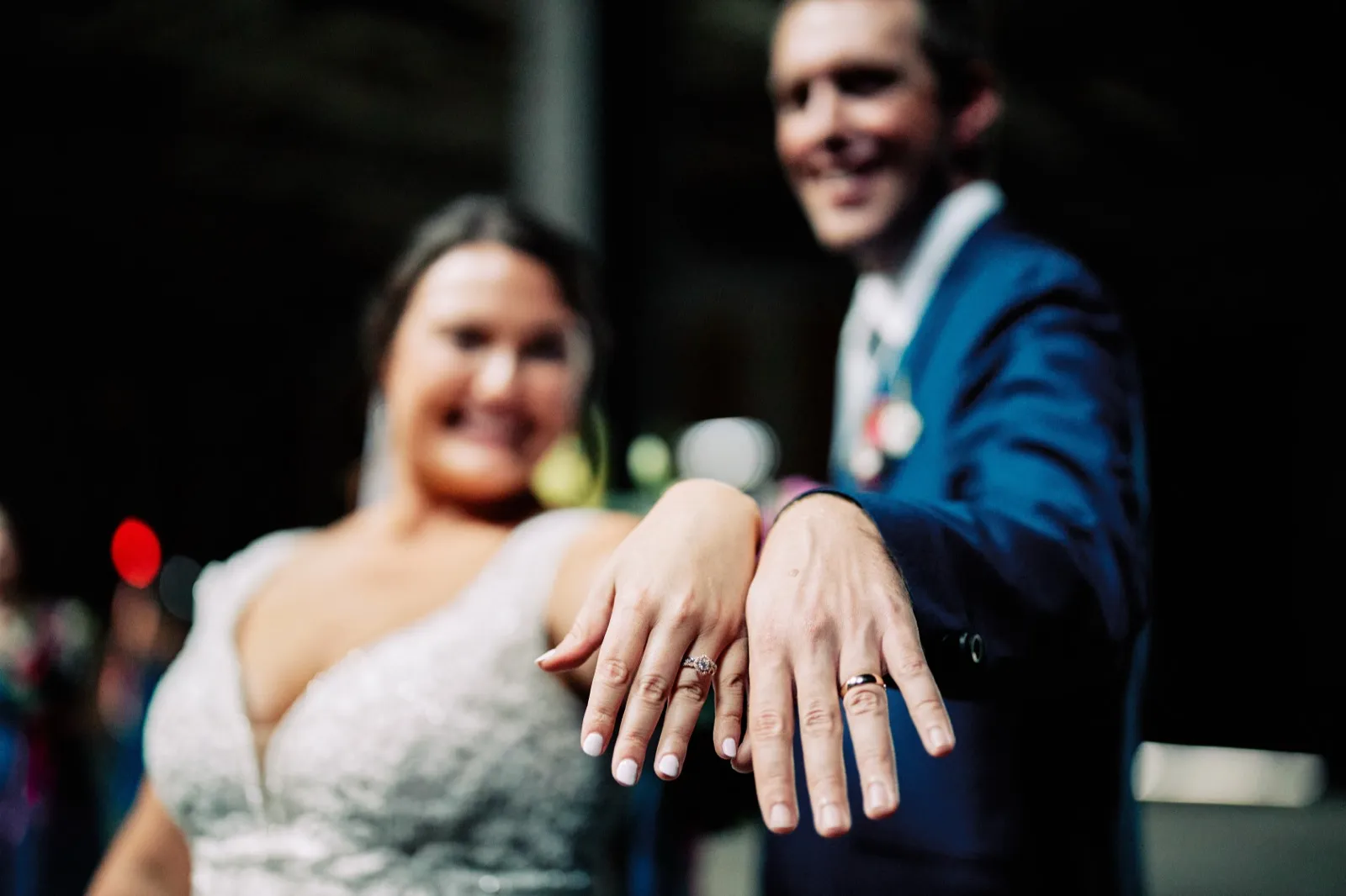 Maggie and Craig hold their hands toward the camera to show their wedding rings, their smiles softly out of focus behind them — Tim Larsen Photography, Brainerd Lakes MN