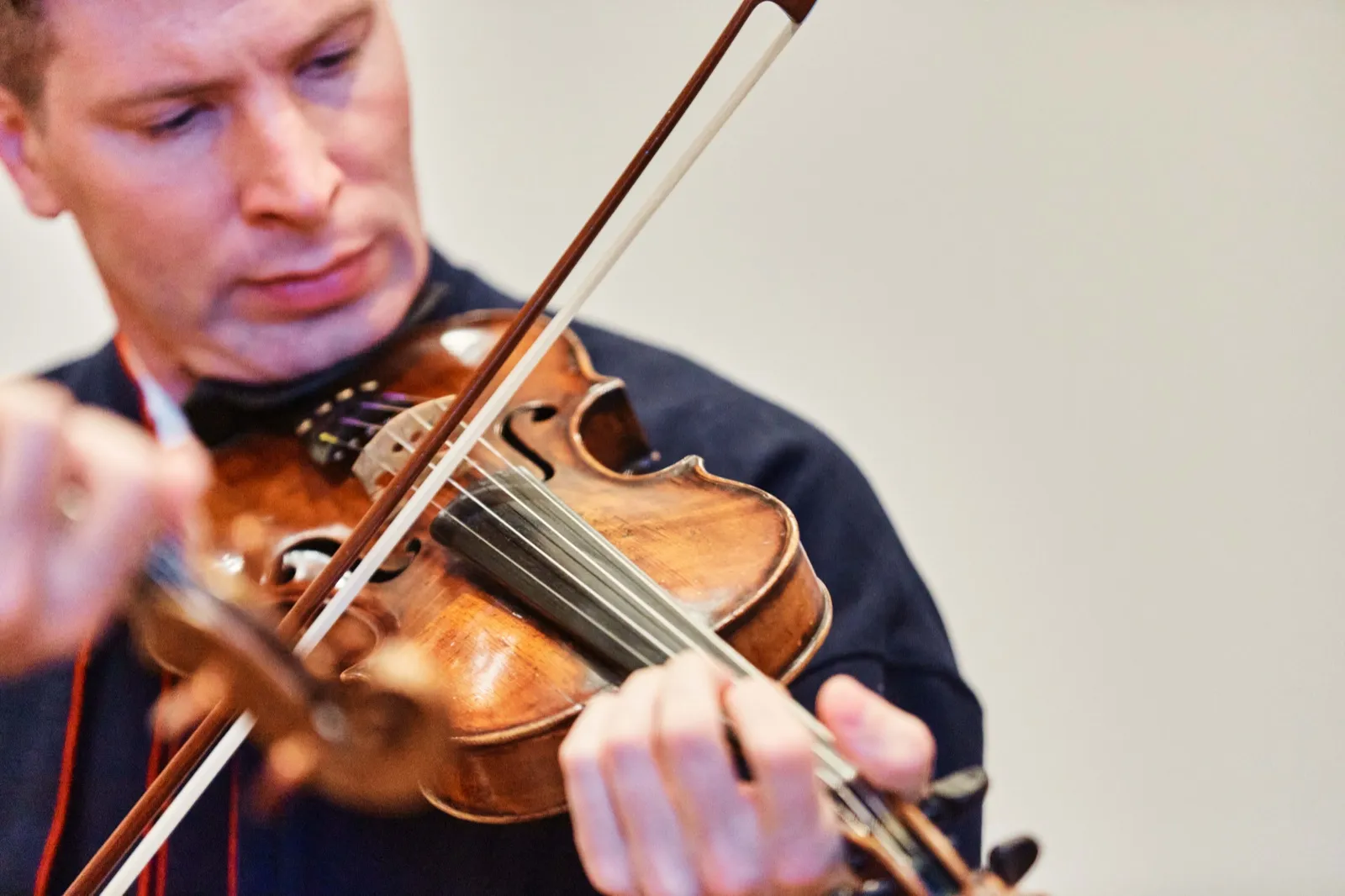 A violinist looks down at his instrument as he draws the bow across the strings during a wedding ceremony. — Tim Larsen Photography, Minnesota