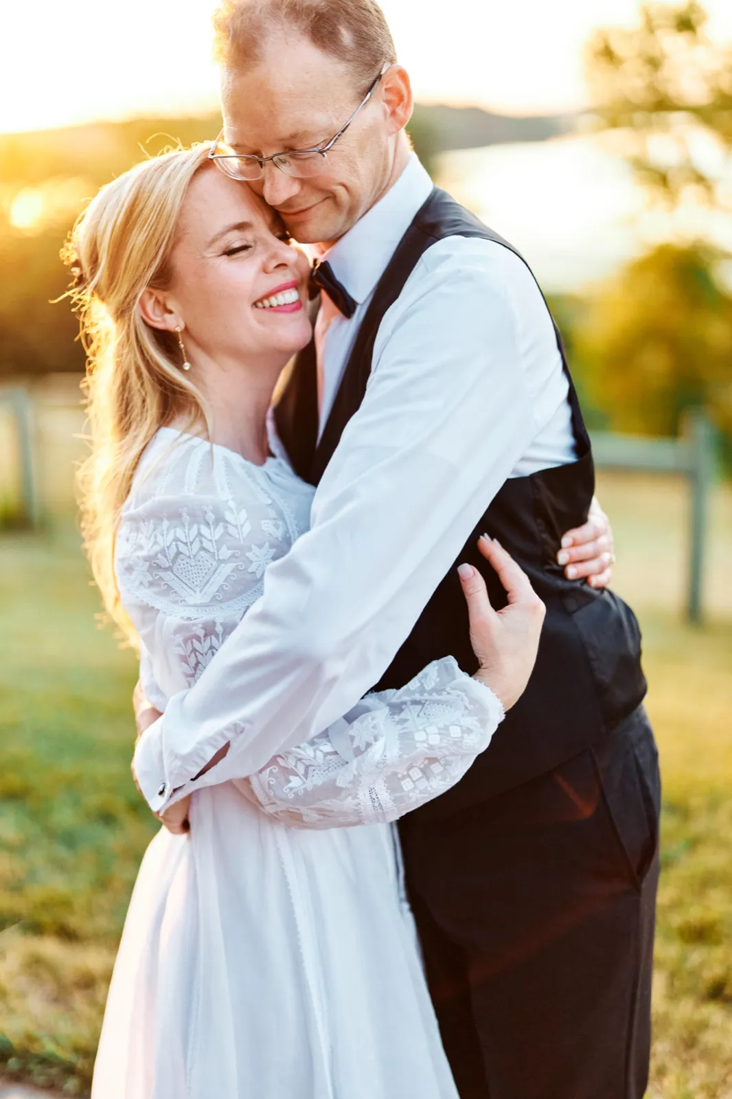 The bride smiles with closed eyes as the groom rests his forehead against her temple during a sunset embrace in an open field. — Tim Larsen Photography, Minnesota