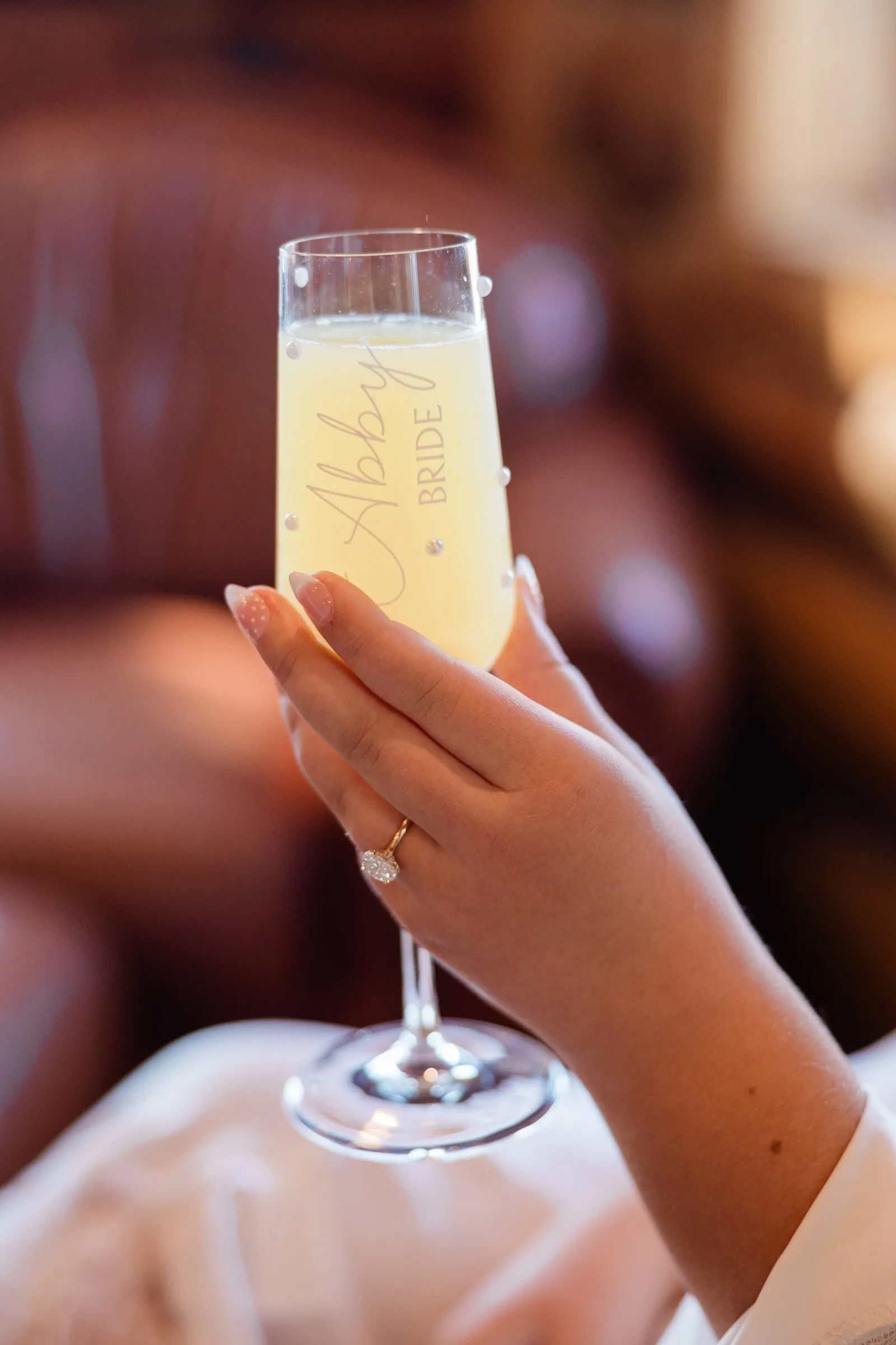 The bride holds a glass labeled Abby Bride, with her engagement ring visible on her hand at The Gathering Lodge — Tim Larsen Photography, Brainerd Lakes MN
