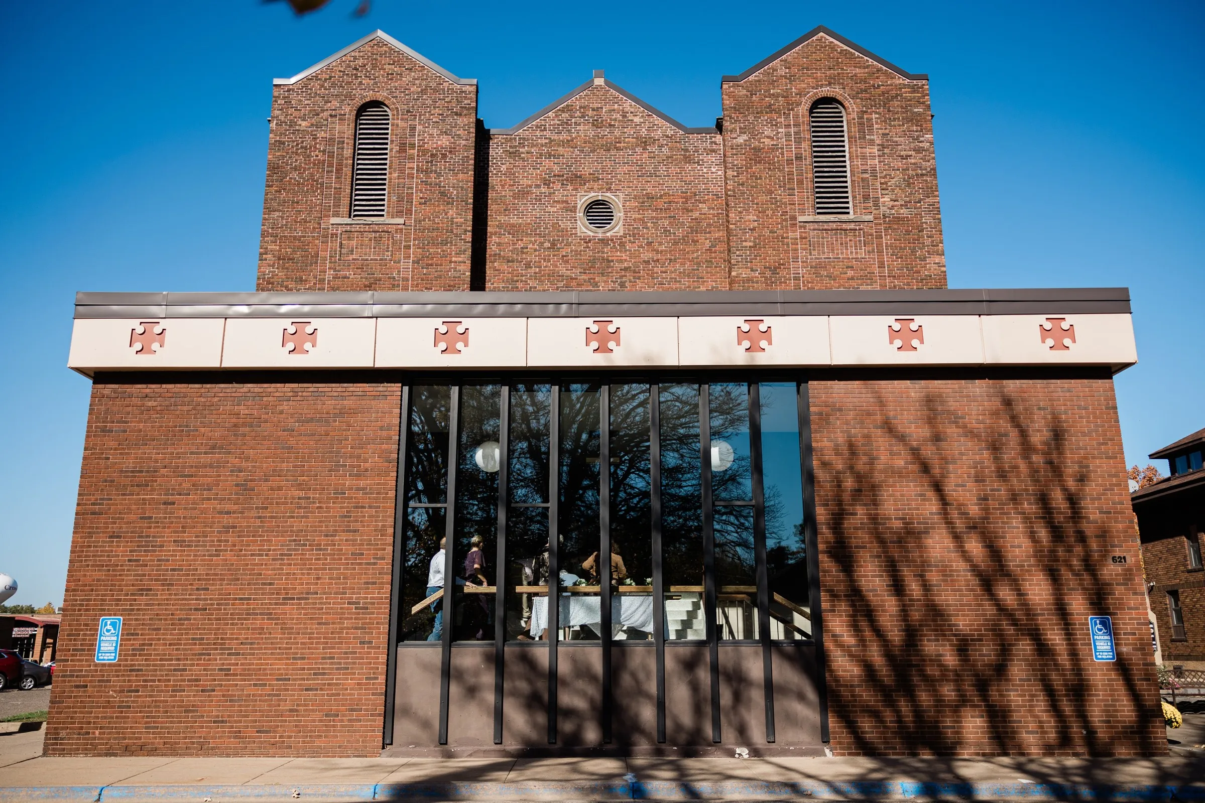 Twin brick towers rise above the glass entry of St. Joseph Catholic Church in Crosby beneath a clear blue sky — Tim Larsen Photography, Brainerd Lakes MN
