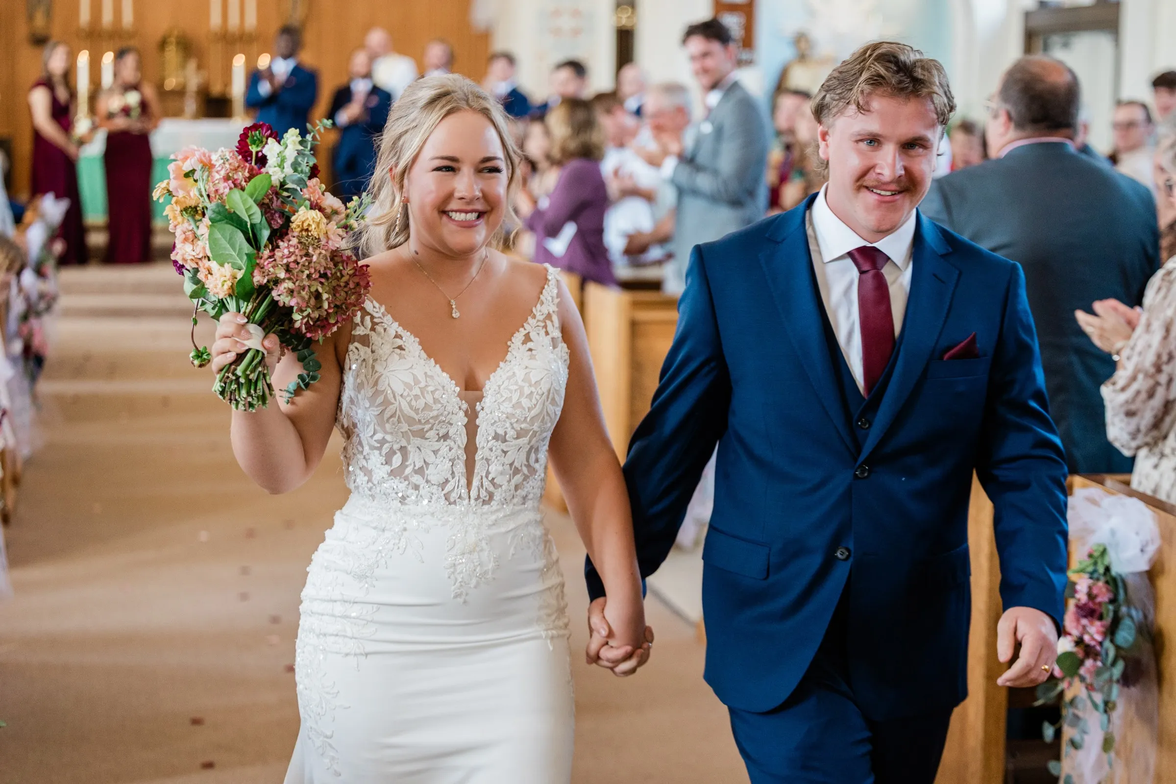 Abby and Anthony smile while walking hand in hand down the aisle at St. Joseph Catholic Church in Crosby — Tim Larsen Photography, Brainerd Lakes MN