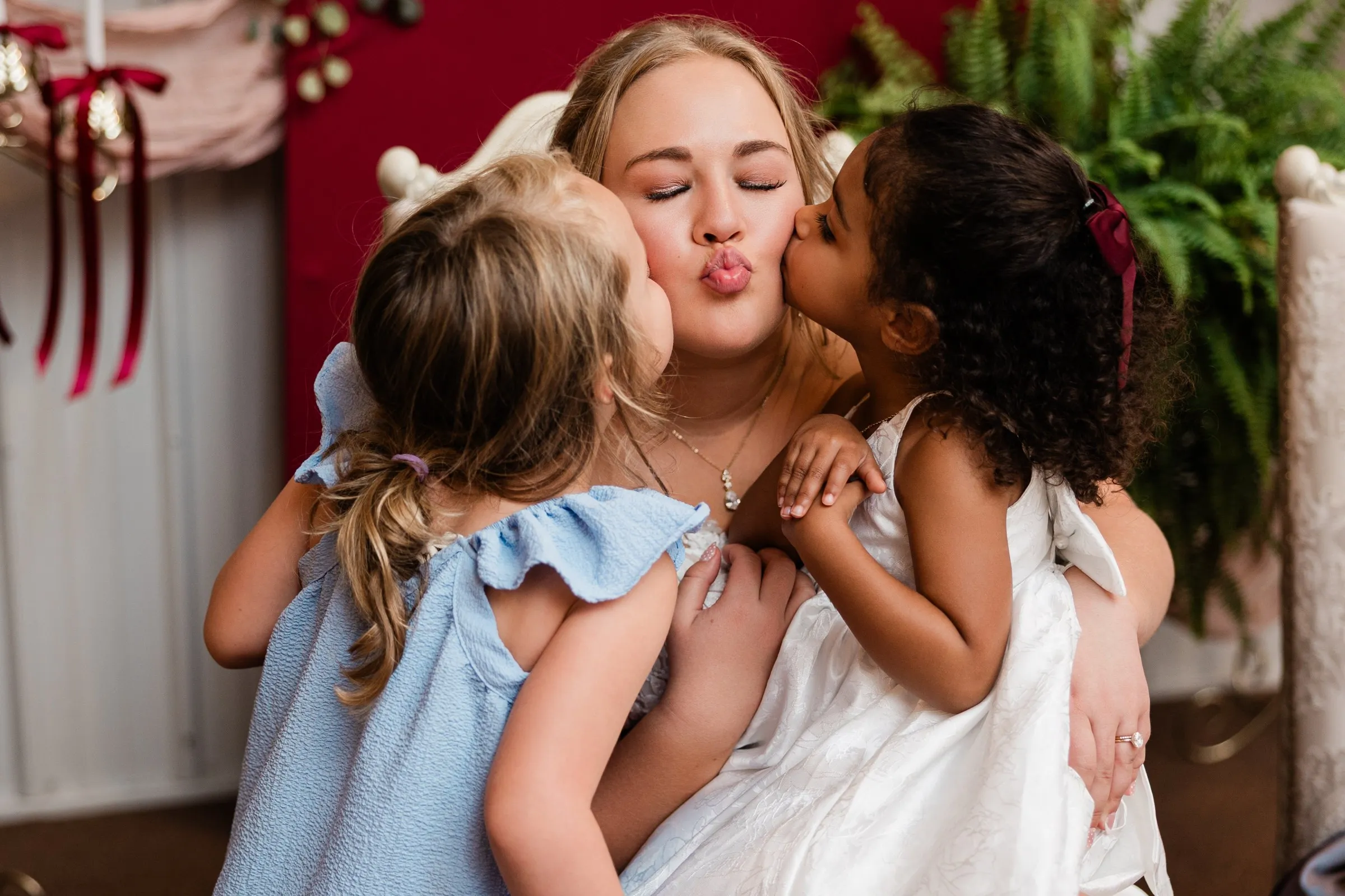 Two young girls kiss the bride on her cheeks as she closes her eyes and puckers her lips at the head table at The Gathering in Crosslake — Tim Larsen Photography, Brainerd Lakes MN