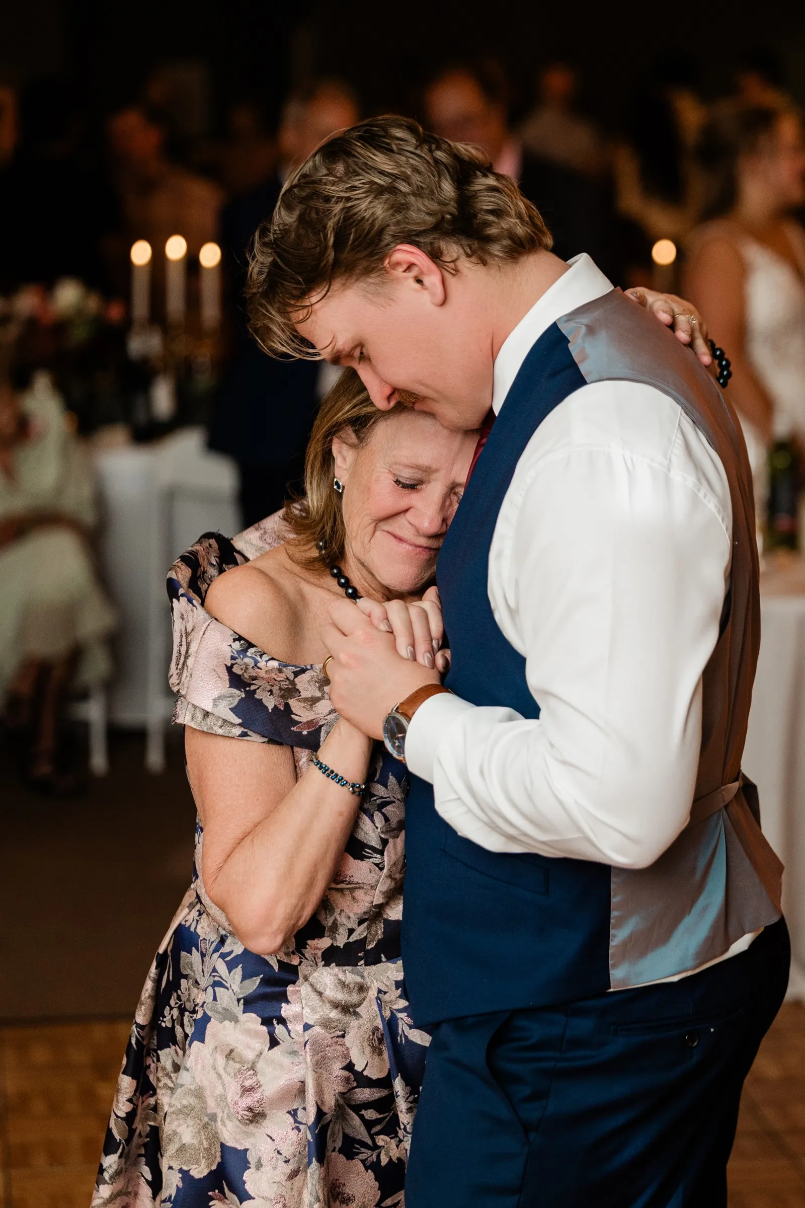 Anthony kisses his mom Kolly’s forehead as she rests against him with closed eyes and their hands clasped at The Gathering in Crosslake — Tim Larsen Photography, Brainerd Lakes MN