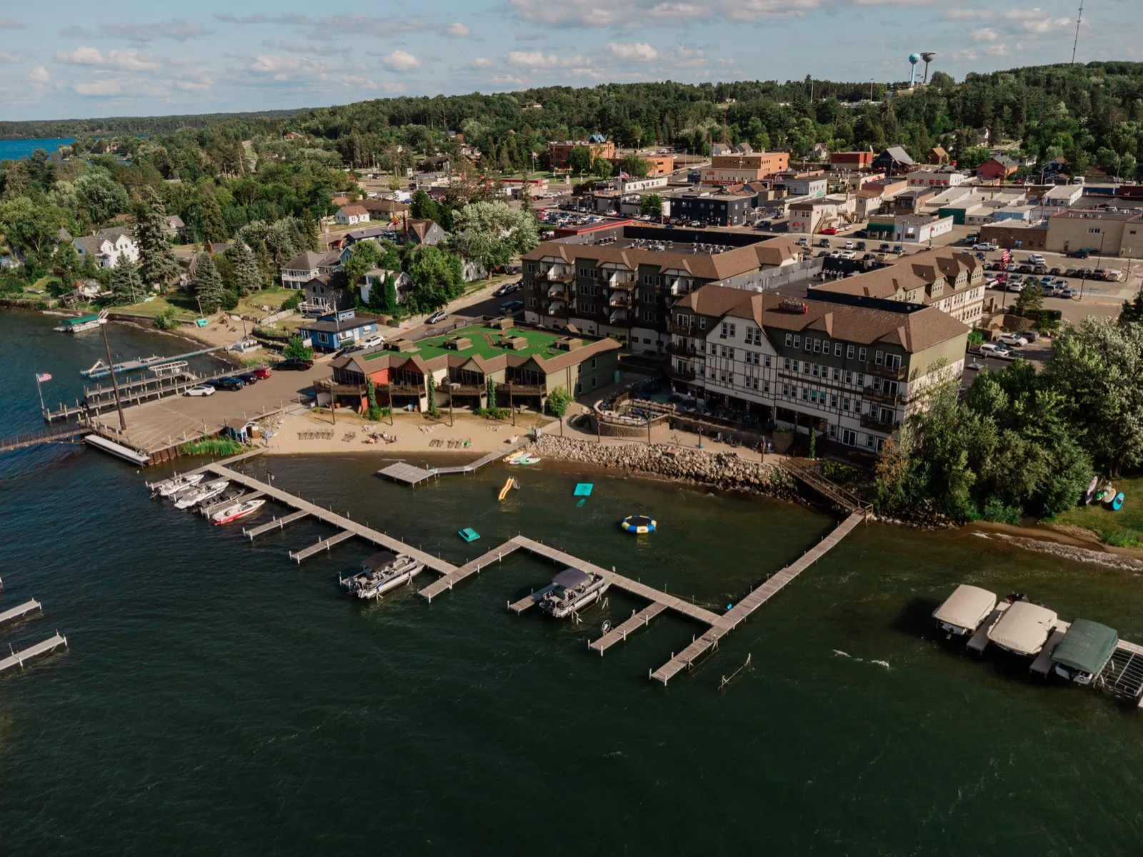 An aerial view of the Chase on the Lake resort in Walker, Minnesota, showing the lodge buildings, sandy beach, and long docks lined with boats on Leech Lake — Tim Larsen Photography, Brainerd Lakes MN