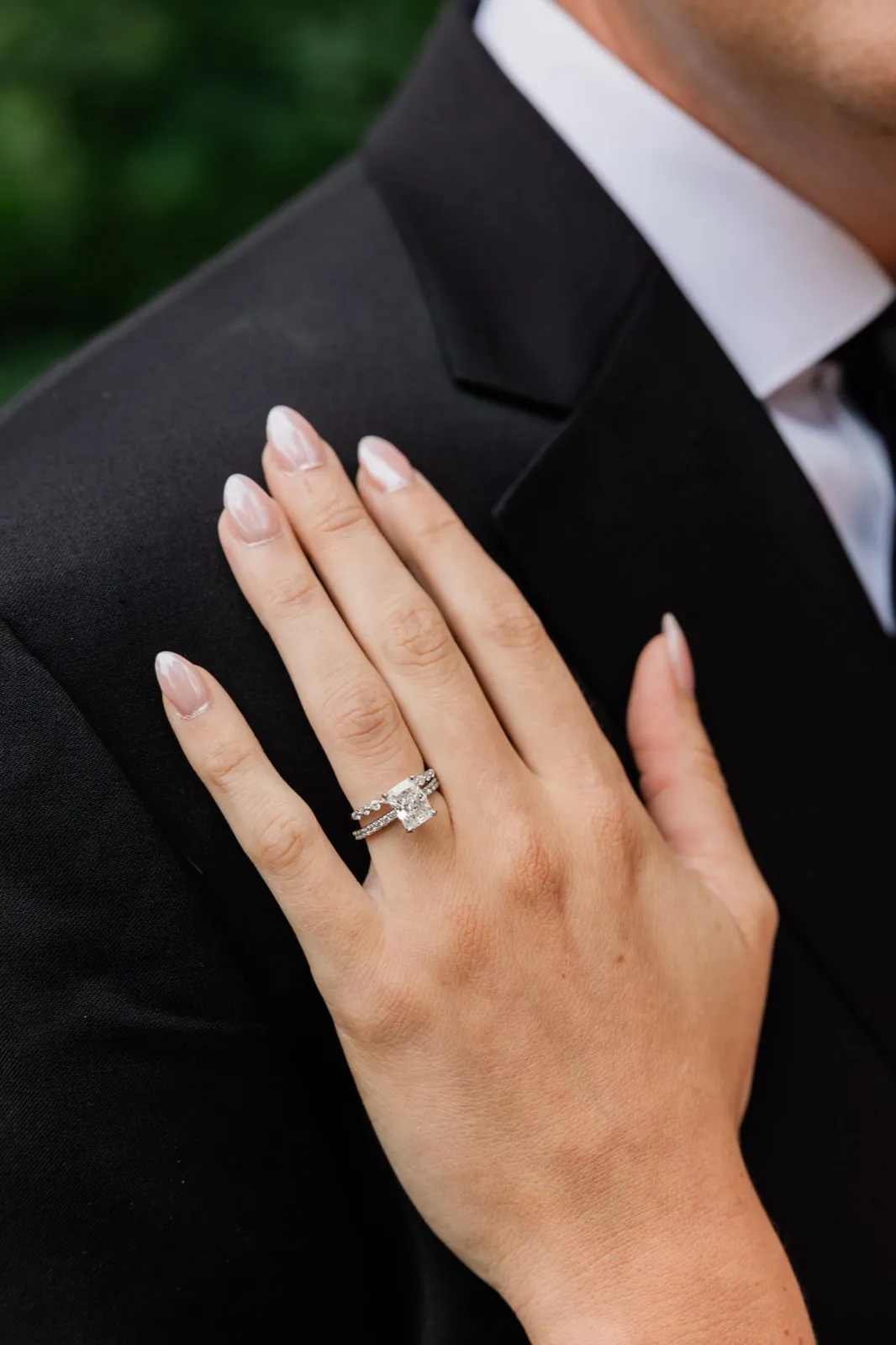 Amy's hand rests on Carter's black suit shoulder, her radiant-cut diamond and twisted pave band catching the light — Tim Larsen Photography, Brainerd Lakes MN