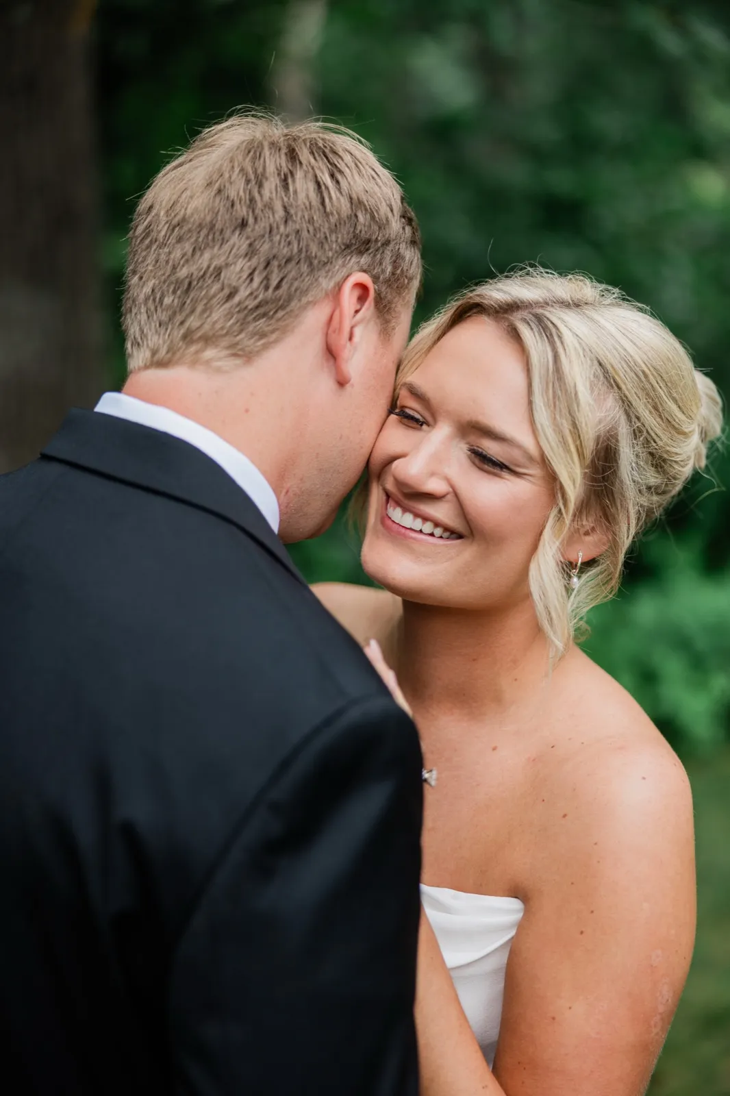 Amy smiles with her eyes nearly closed as Carter presses his face to her cheek in the green shade — Tim Larsen Photography, Brainerd Lakes MN