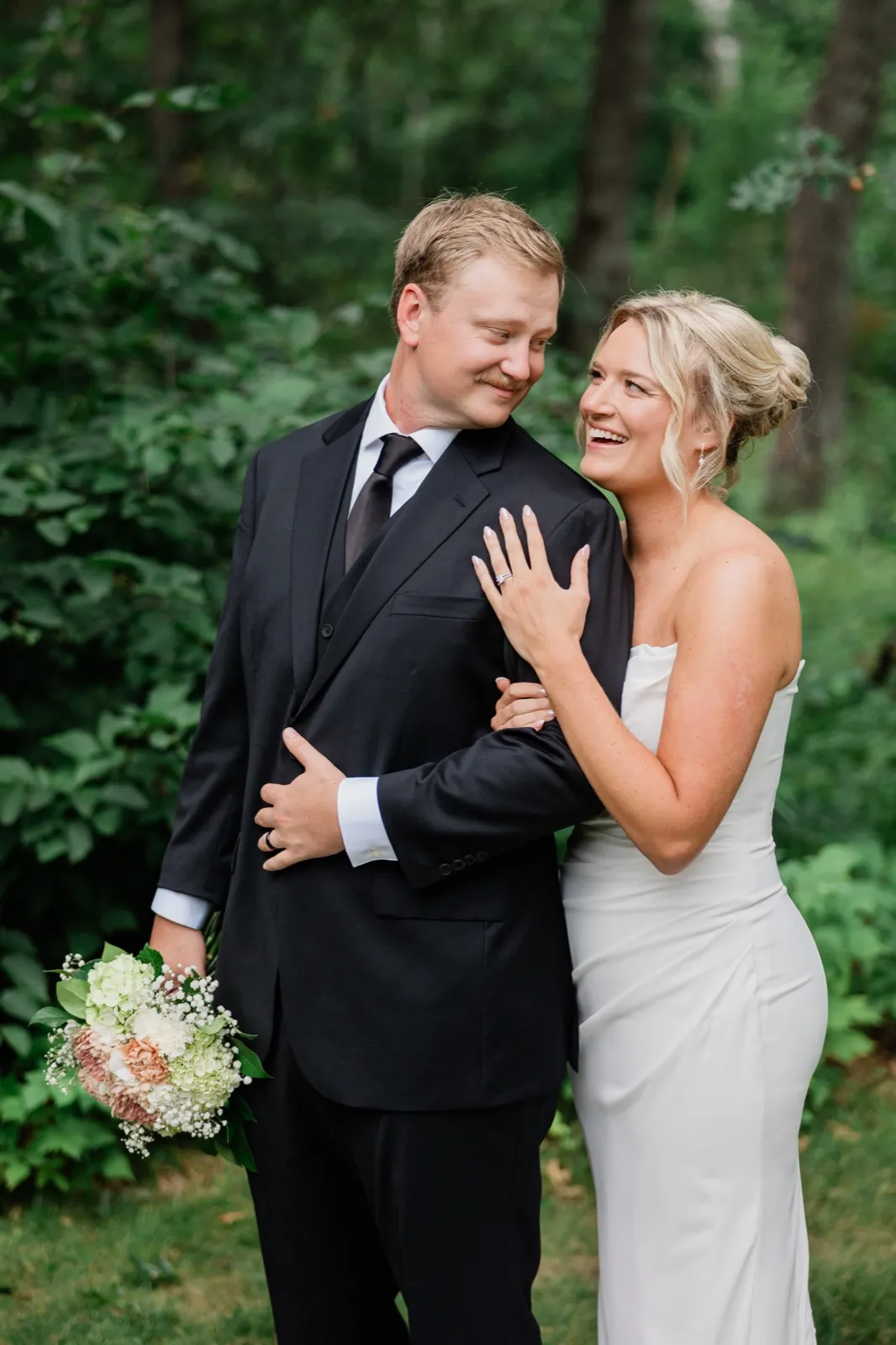 Amy laughs with a hand on Carter's chest while he holds her bouquet at his side — Tim Larsen Photography, Brainerd Lakes MN