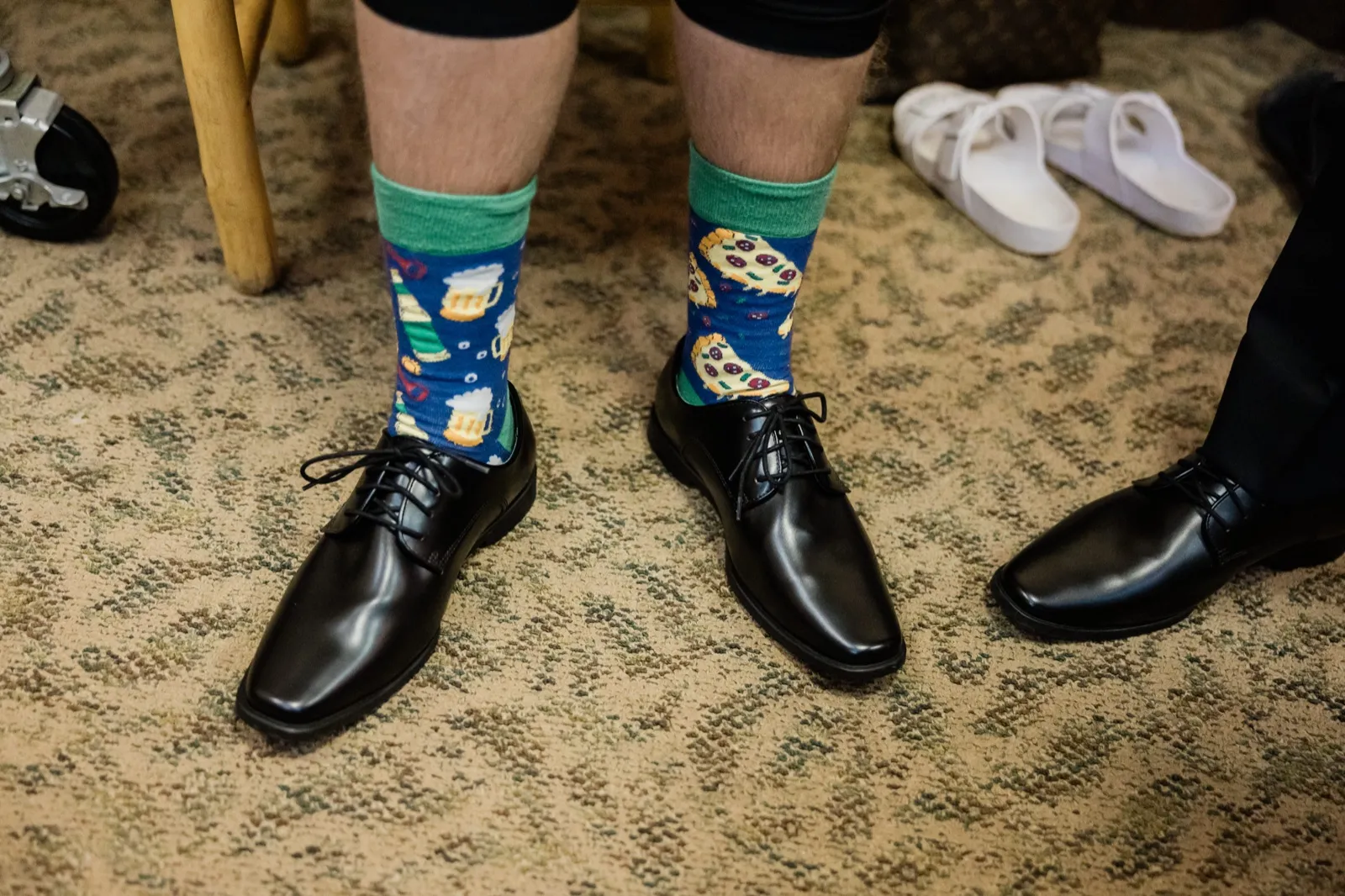 Pizza-and-beer patterned socks with green cuffs showing above black dress shoes before the ceremony — Tim Larsen Photography, Brainerd Lakes MN