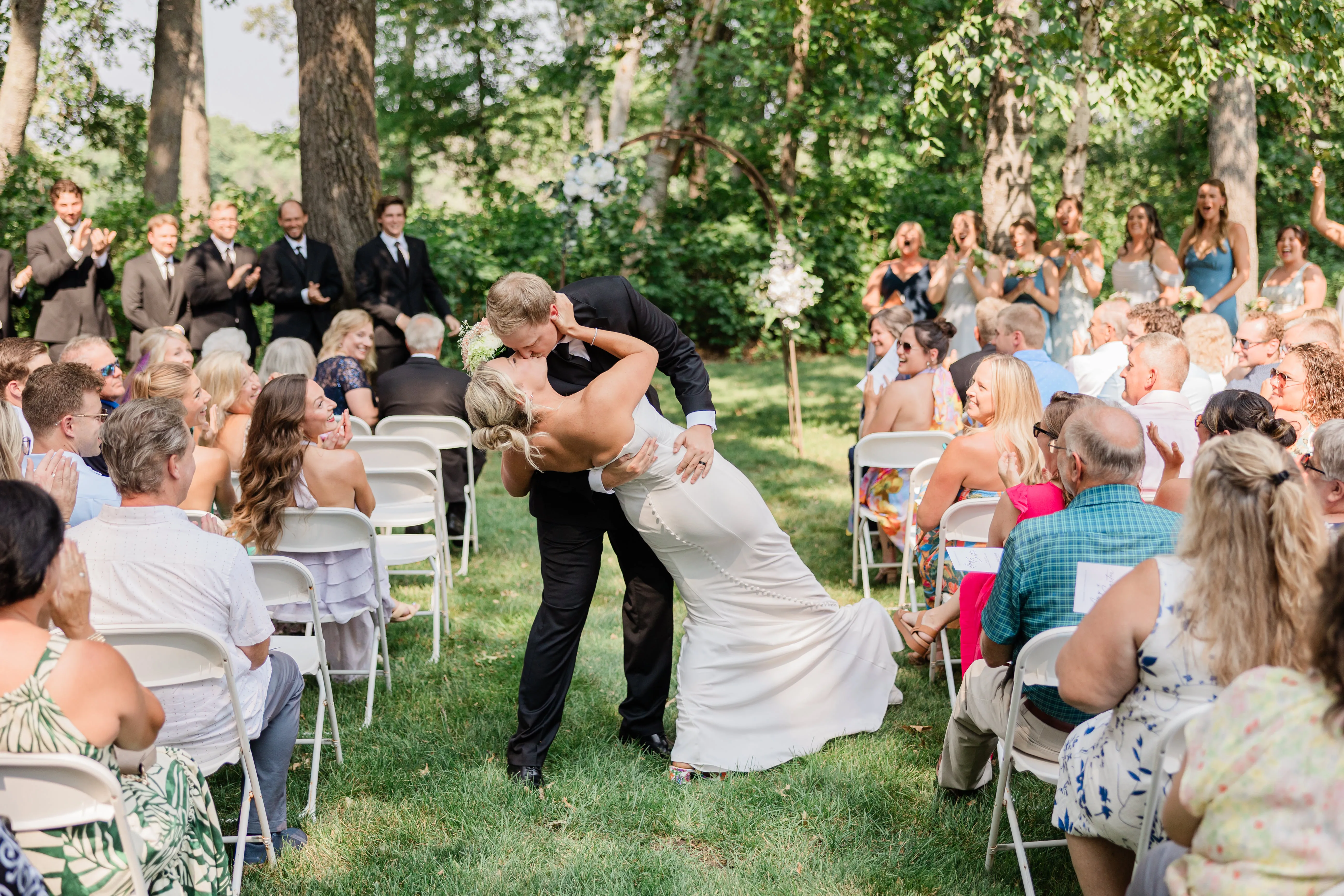 Carter dips Amy for a kiss in the middle of the aisle at Whitefish Lodge while the entire seated crowd applauds — Tim Larsen Photography, Brainerd Lakes MN