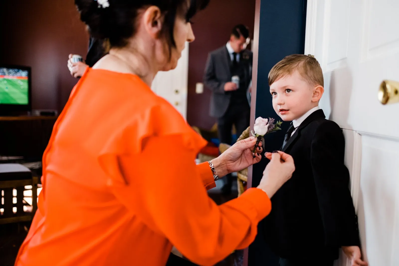 Mother pins the young ring bearer's boutonniere at the door — Duluth Catholic spring wedding getting-ready candid — Tim Larsen Photography, Duluth MN