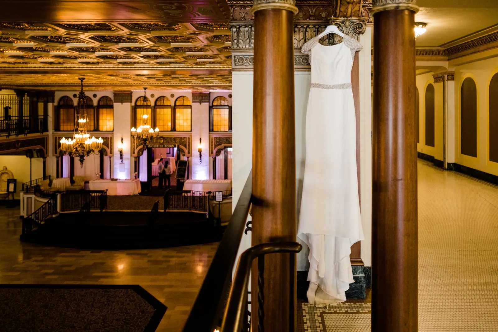 Wedding dress hangs between ornate columns overlooking the Moorish Room ballroom — historic Greysolon Plaza, Duluth Catholic wedding — Tim Larsen Photography, Duluth MN