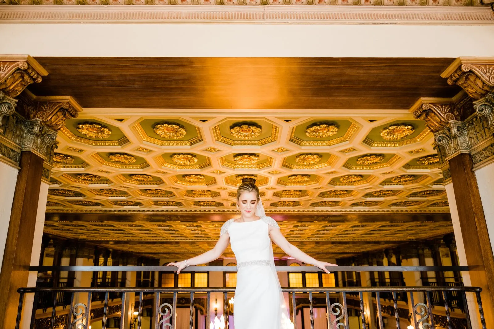 Bride and groom on the gilded mezzanine balcony at the Greysolon Plaza, arms outstretched under the coffered ceiling — Duluth Catholic wedding portrait — Tim Larsen Photography, Duluth MN