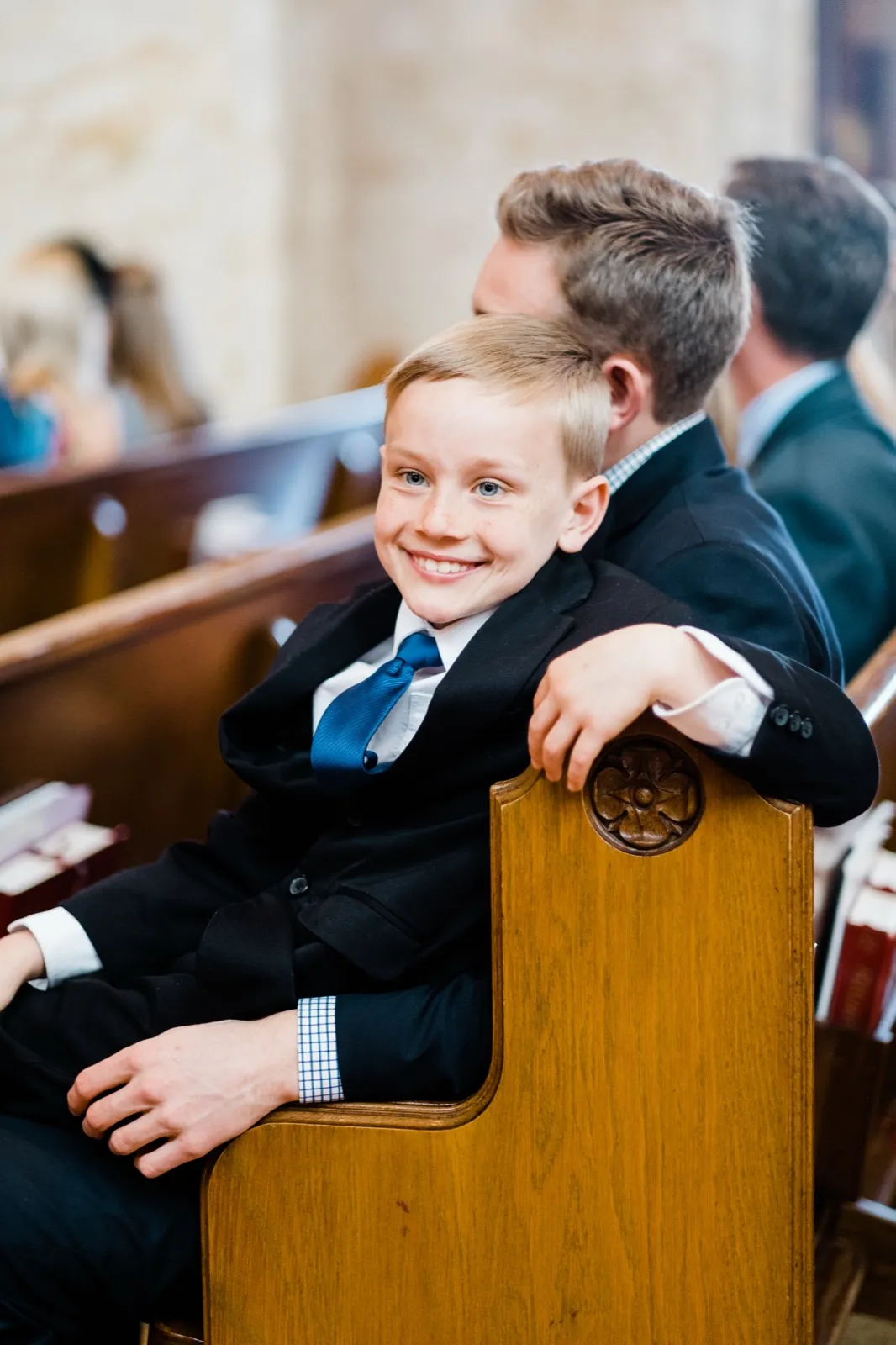 Young boy peers over a carved pew end before the ceremony begins — Cathedral of Our Lady of the Rosary, Duluth Catholic wedding candid — Tim Larsen Photography, Duluth MN