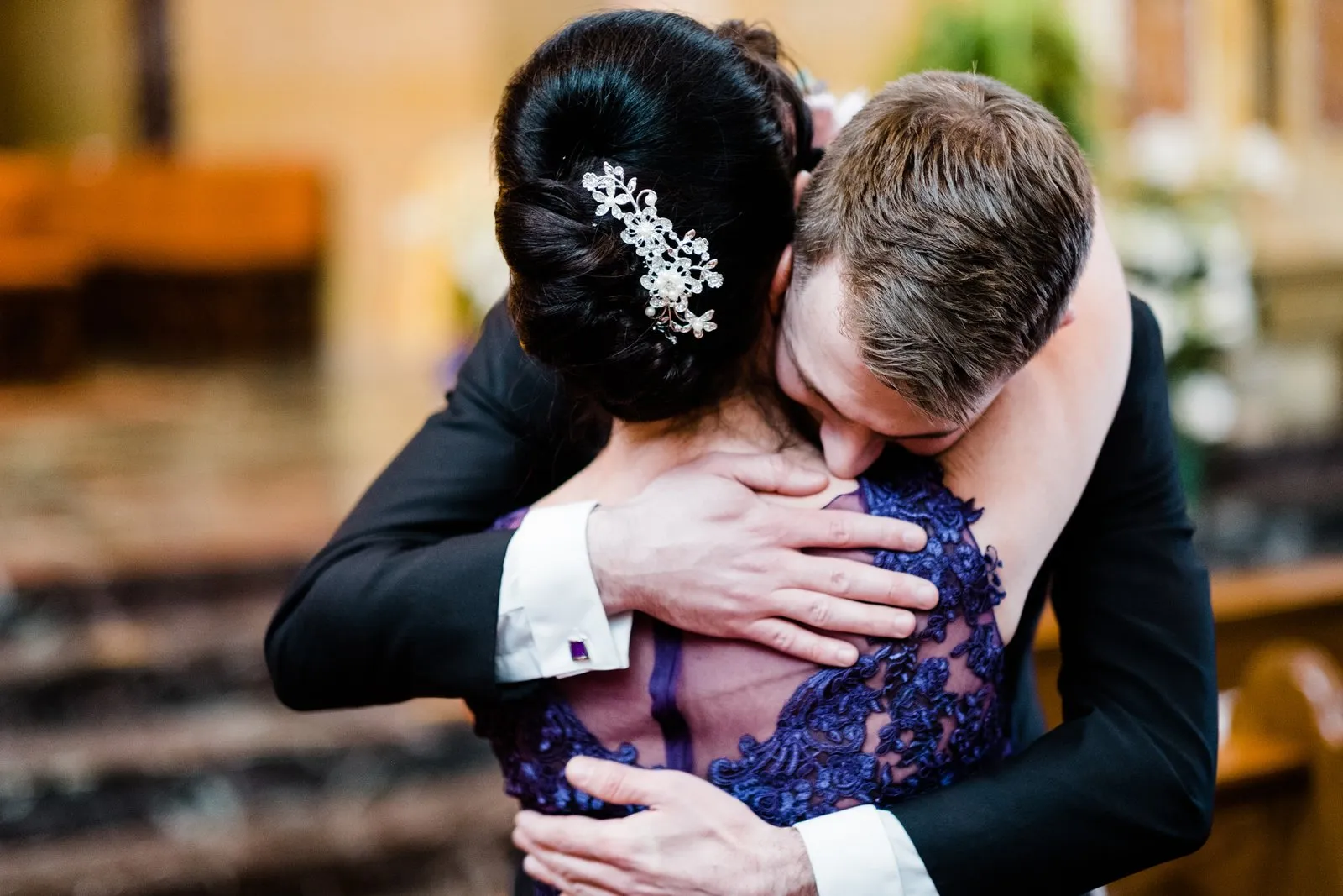 Tight embrace from behind the bride after the ceremony — ornate hairpiece and lace gown anchor the frame, Cathedral of Our Lady of the Rosary — Tim Larsen Photography, Duluth MN