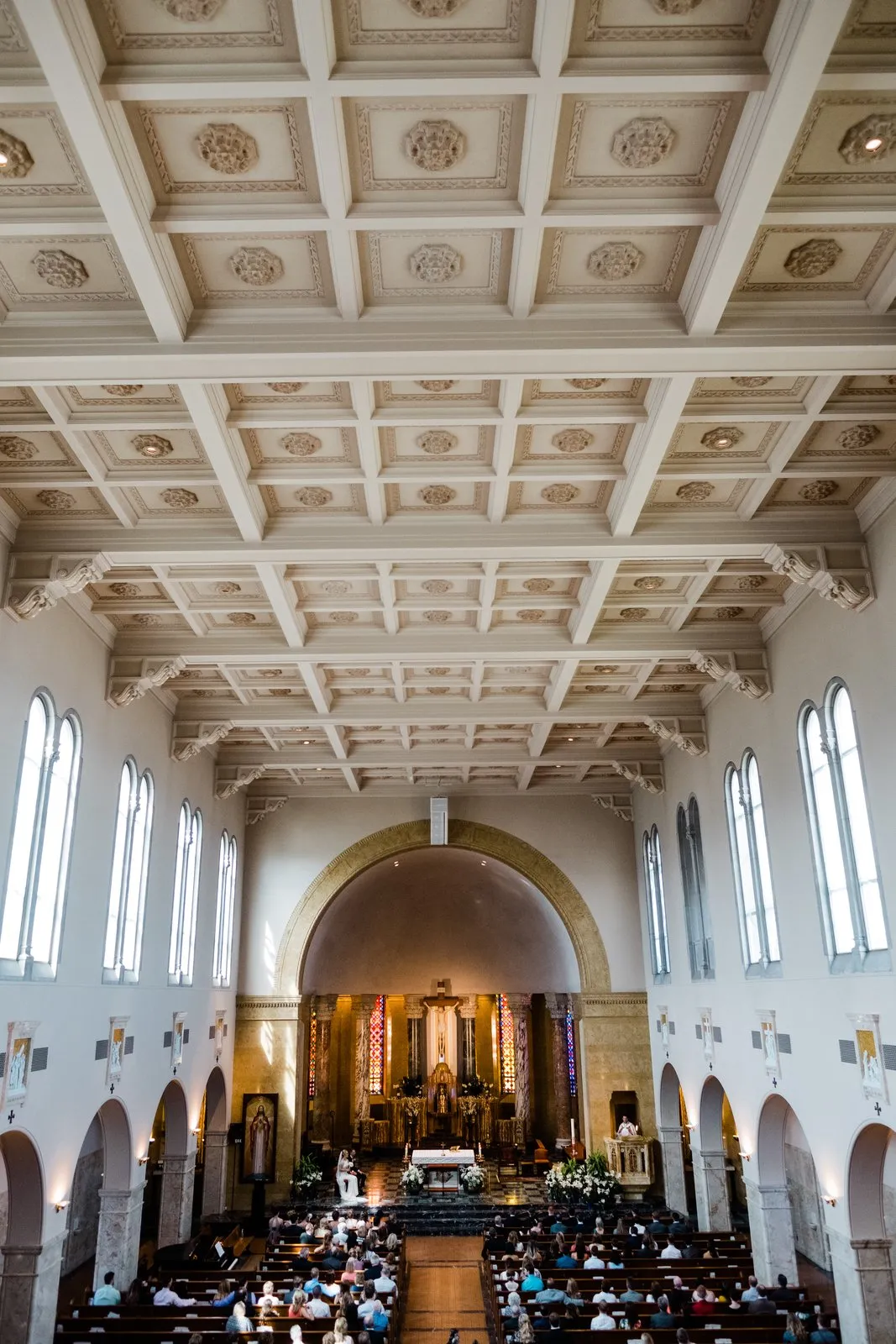 Sweeping wide of the Cathedral of Our Lady of the Rosary sanctuary — coffered ceiling, arched windows, the couple at the distant altar — Duluth Catholic wedding — Tim Larsen Photography, Duluth MN