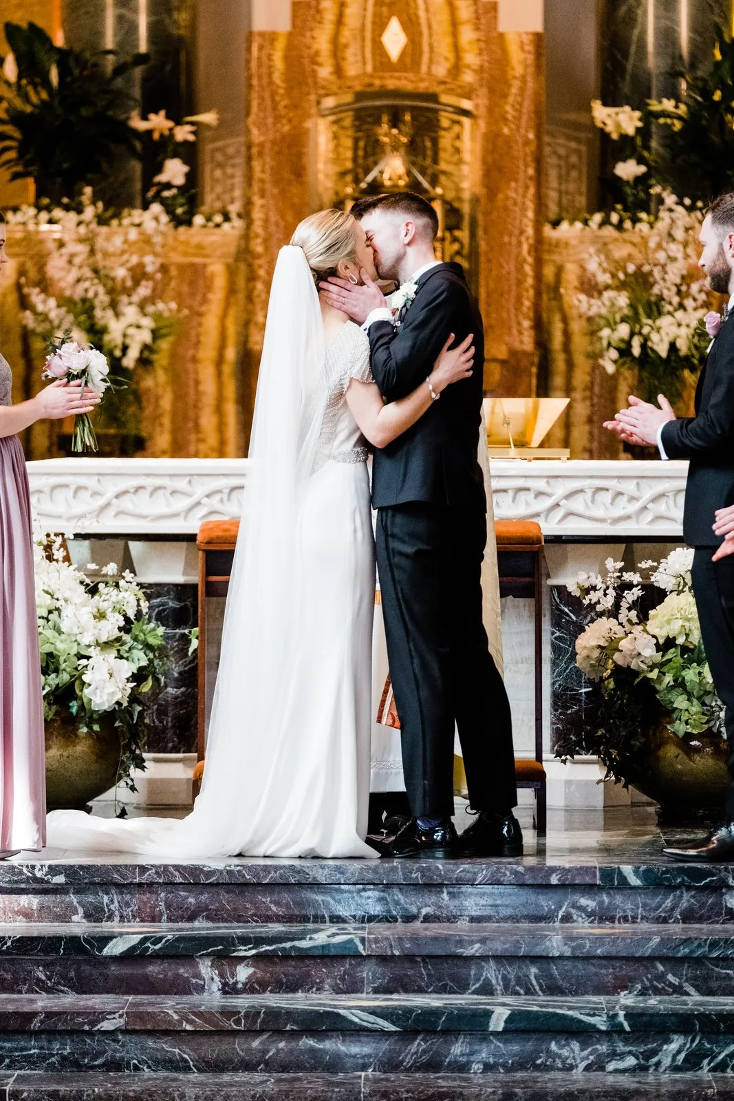 First kiss framed by the ornate altar and white florals as attendants clap — Cathedral of Our Lady of the Rosary, Duluth Catholic wedding — Tim Larsen Photography, Duluth MN