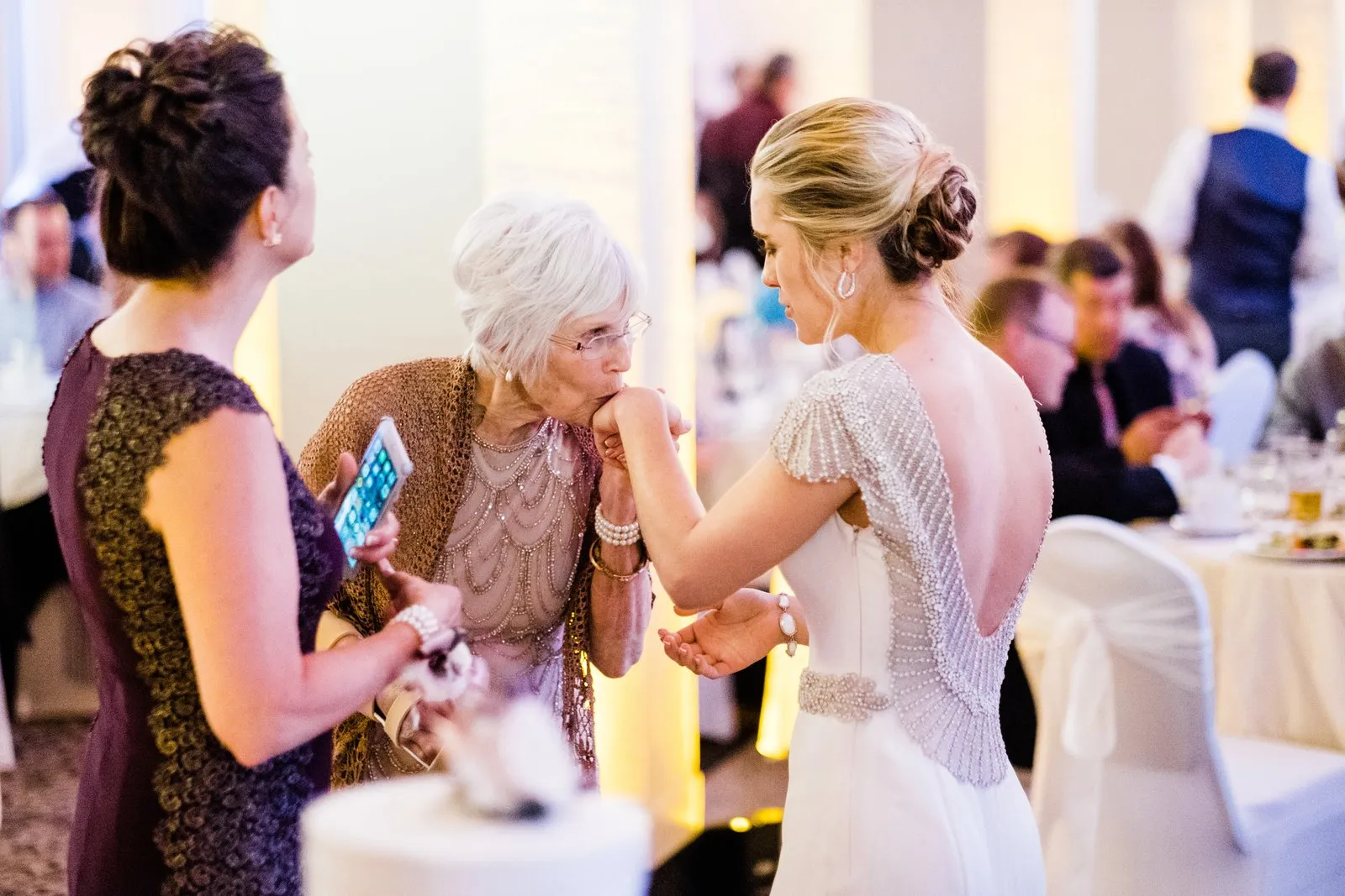 Elder relative kisses the bride's hand mid-reception — intimate gesture at the Greysolon Ballroom, Duluth Catholic spring wedding — Tim Larsen Photography, Duluth MN