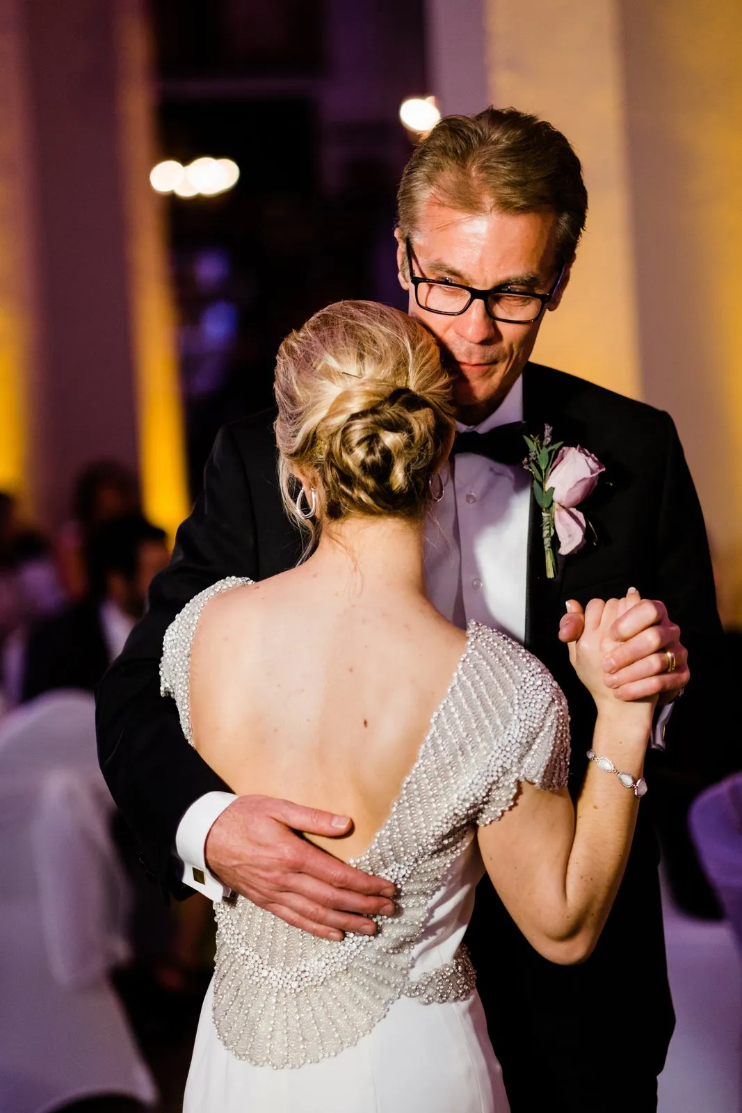 Father's emotive face above the bride's back during their father-daughter dance, beaded gown catching warm uplight — Greysolon Ballroom Duluth — Tim Larsen Photography, Duluth MN