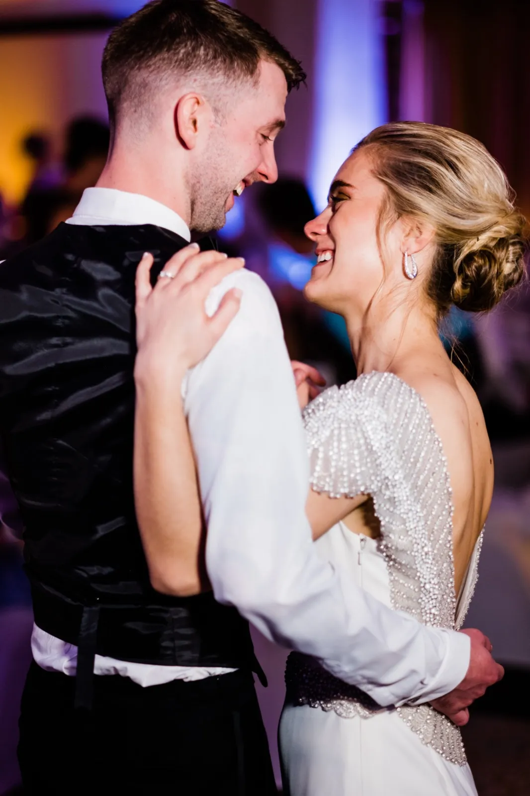 Tight first-dance two-shot, both faces lit, purple uplighting bokeh framing the historic Greysolon Ballroom — Duluth Catholic spring wedding — Tim Larsen Photography, Duluth MN