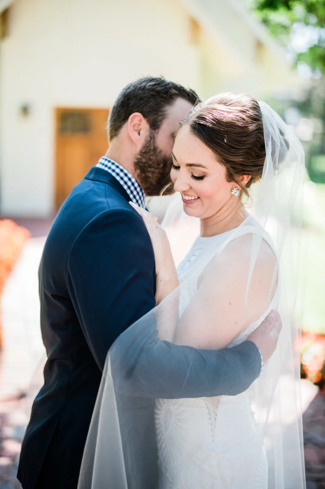 The bride smiles softly with eyes closed as the groom leans his forehead against hers, her veil draping across his arm. — Tim Larsen Photography, Brainerd Lakes MN