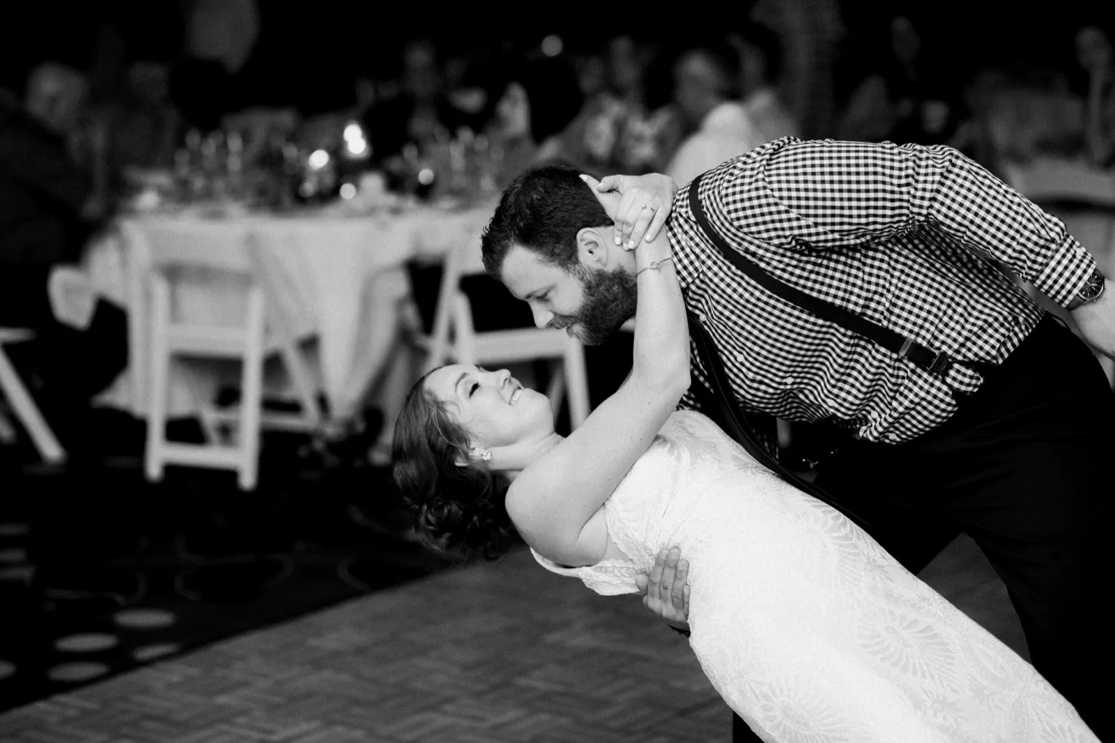 In black and white, the groom dips the bride backward on the dance floor as she laughs with her head tilted back. — Tim Larsen Photography, Brainerd Lakes MN