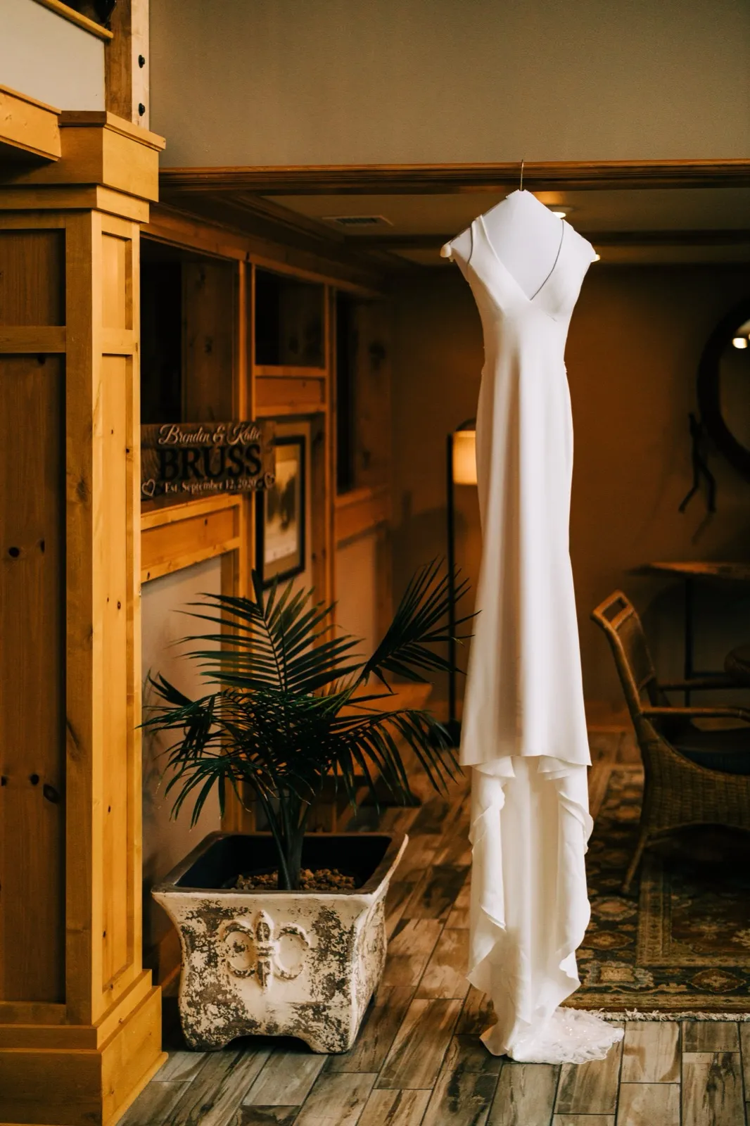 Katie's white gown hangs from a wooden beam beside a custom family-name sign in the warm-toned lodge interior at Madden's — Tim Larsen Photography, Brainerd Lakes MN
