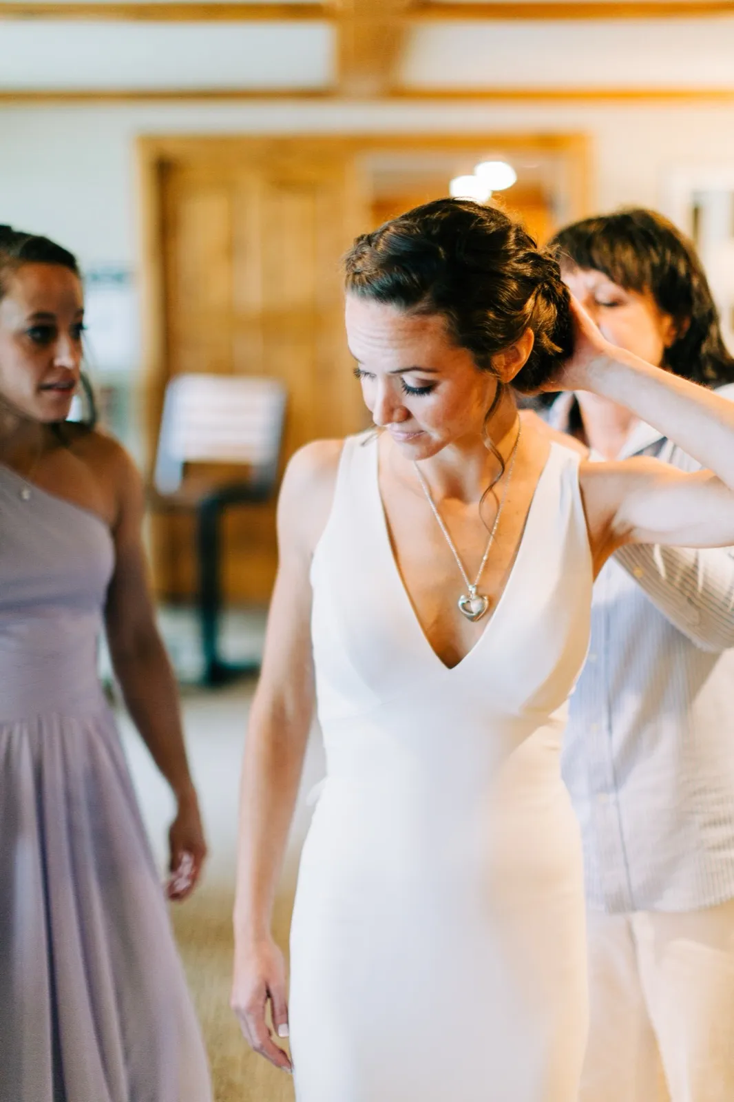 Katie looks down as her mother fastens a heart-pendant necklace at her neck in the getting-ready room at Madden's — Tim Larsen Photography, Brainerd Lakes MN