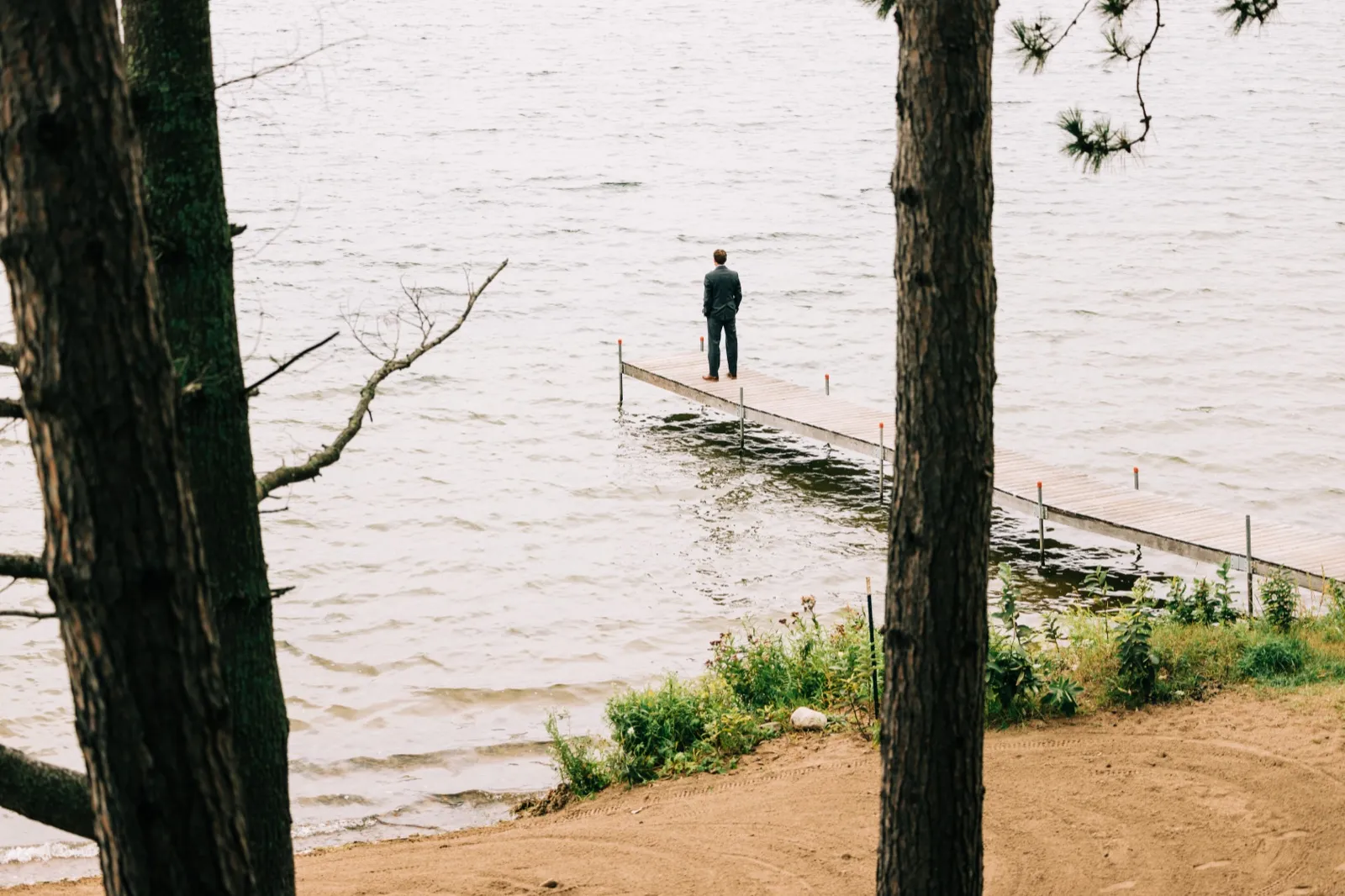 Brenden waits alone at the end of a long dock on Gull Lake for the first look, framed between two pine trunks — Tim Larsen Photography, Brainerd Lakes MN