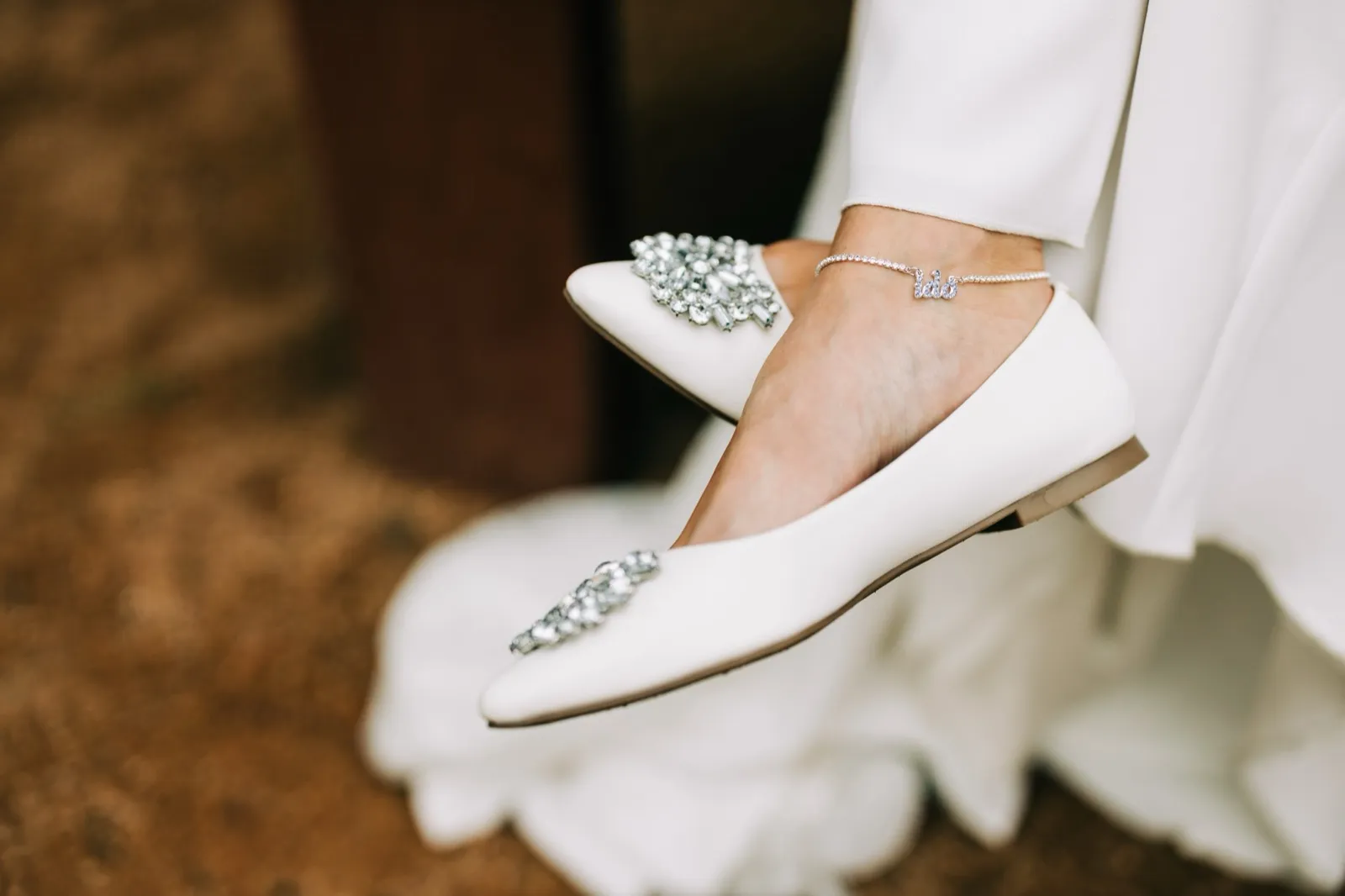 Katie's jeweled white flats and a delicate 'I do' anklet, gown hem pooling beneath — Tim Larsen Photography, Brainerd Lakes MN
