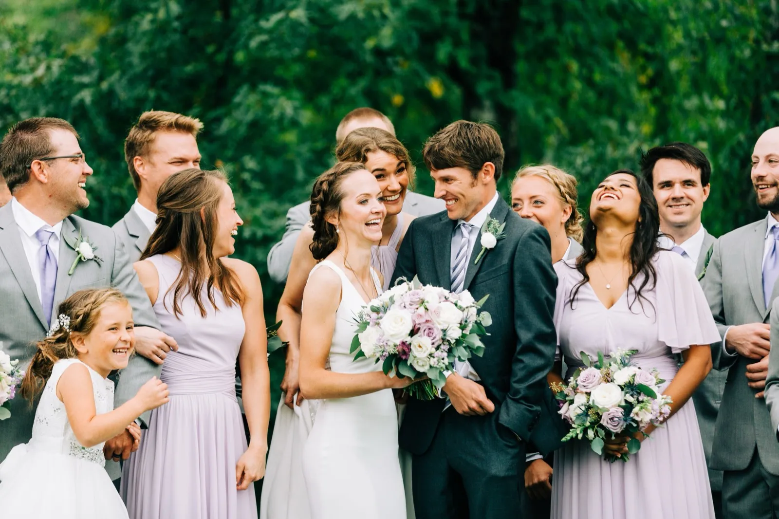 Katie and Brenden laugh with their bridal party and a young flower girl, everyone reacting with genuine joy — Tim Larsen Photography, Brainerd Lakes MN