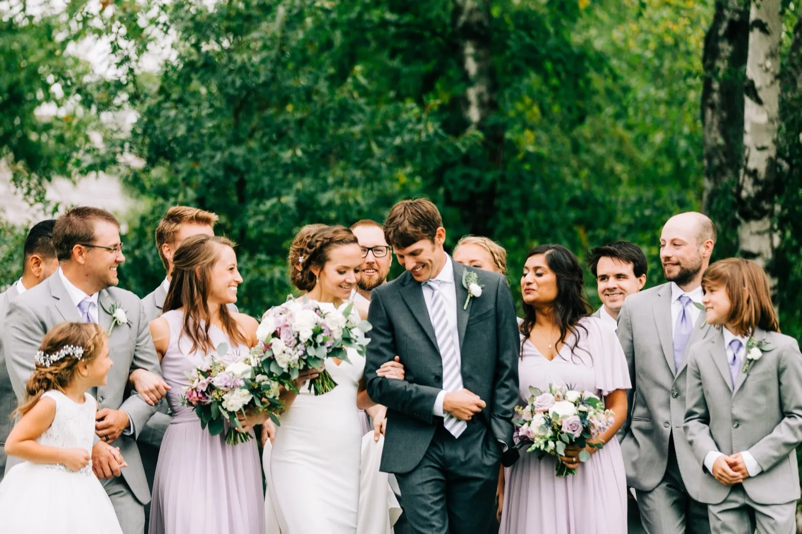 Katie and Brenden walk arm in arm with their bridal party in lavender and grey, a flower girl and ring bearer at either end — Tim Larsen Photography, Brainerd Lakes MN