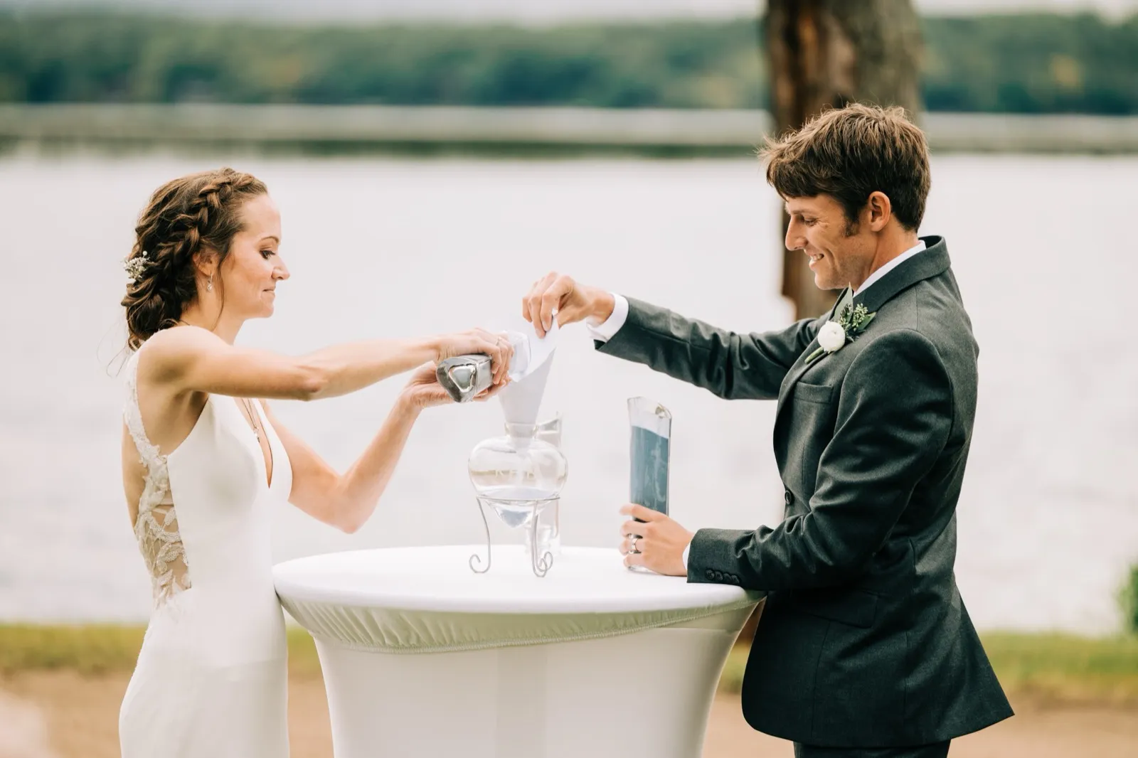 Katie and Brenden pour colored sand together into a glass vessel during their lakeside ceremony at Madden's on Gull Lake — Tim Larsen Photography, Brainerd Lakes MN
