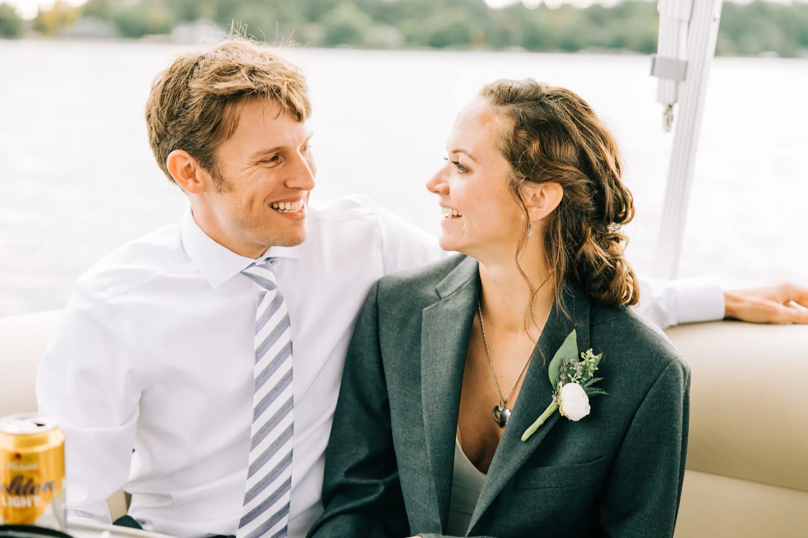 Katie and Brenden turn to each other and laugh on a pontoon boat, Gull Lake softly visible behind them — Tim Larsen Photography, Brainerd Lakes MN