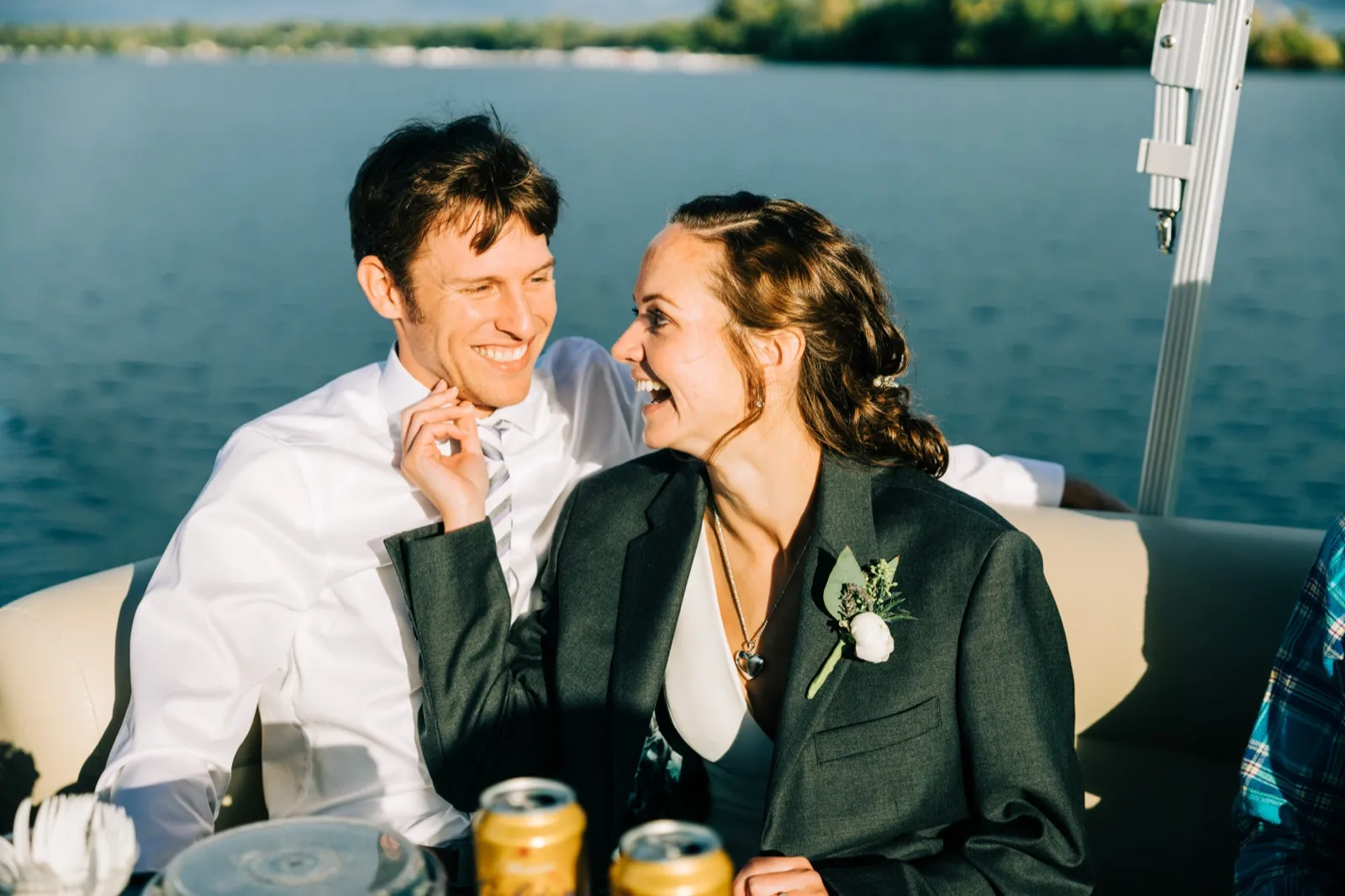Katie, wrapped in Brenden's suit jacket, laughs with Brenden on a pontoon, Gull Lake behind them — Tim Larsen Photography, Brainerd Lakes MN