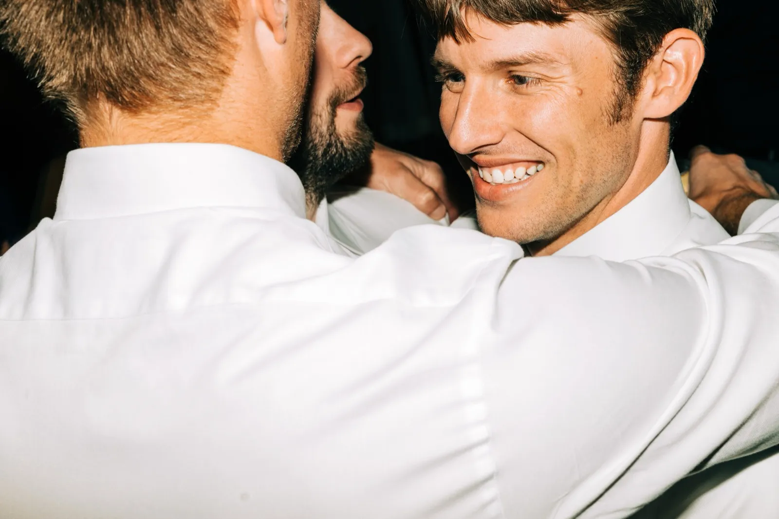 Brenden grins as he embraces a friend on the dance floor, lit by direct flash — Tim Larsen Photography, Brainerd Lakes MN